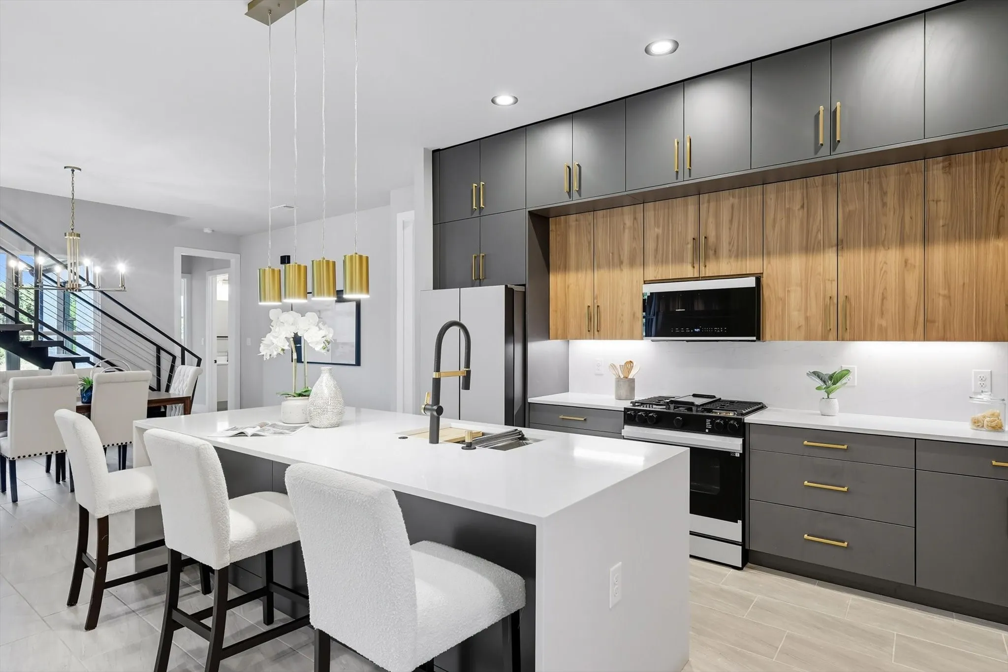 Kitchen with gray cabinetry, a kitchen breakfast bar, black gas range, pendant lighting, and modern cabinets
