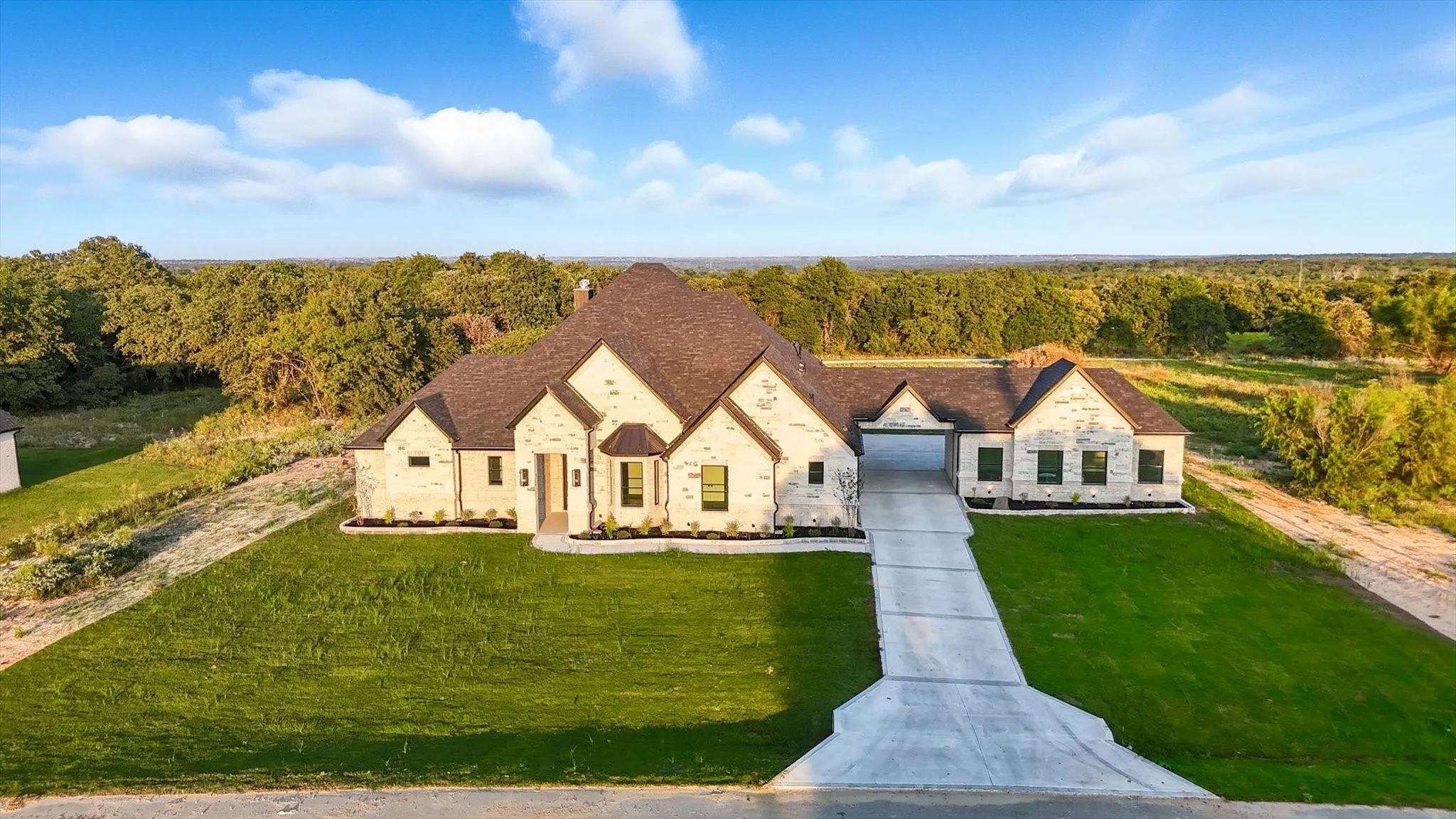 French country home with a front yard, stone siding, a wooded view, and a chimney