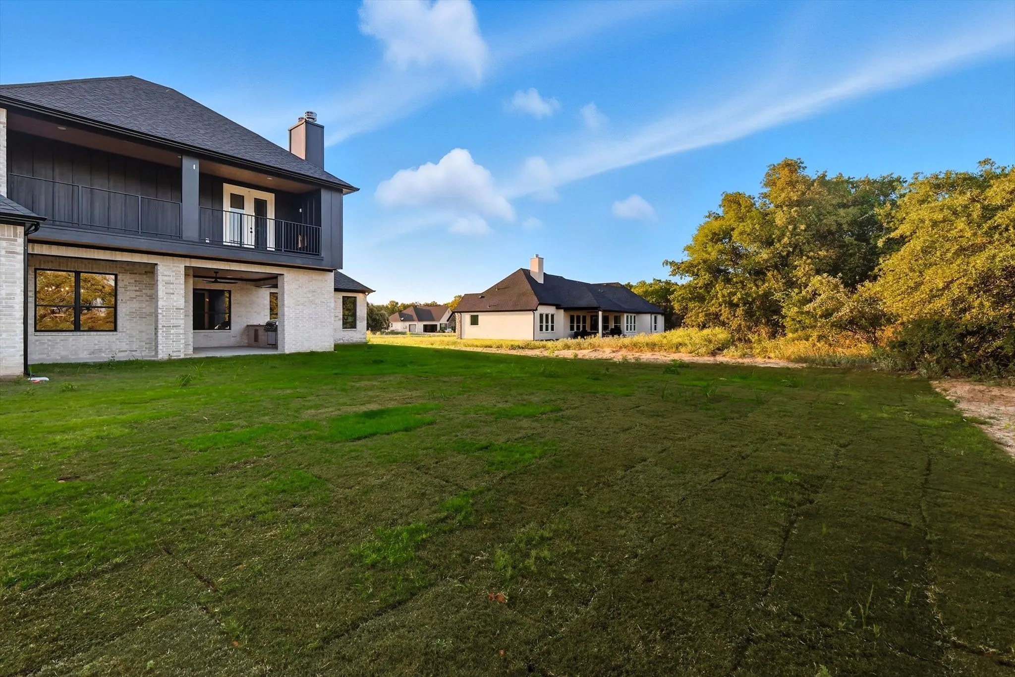 View of green lawn with a patio and a balcony