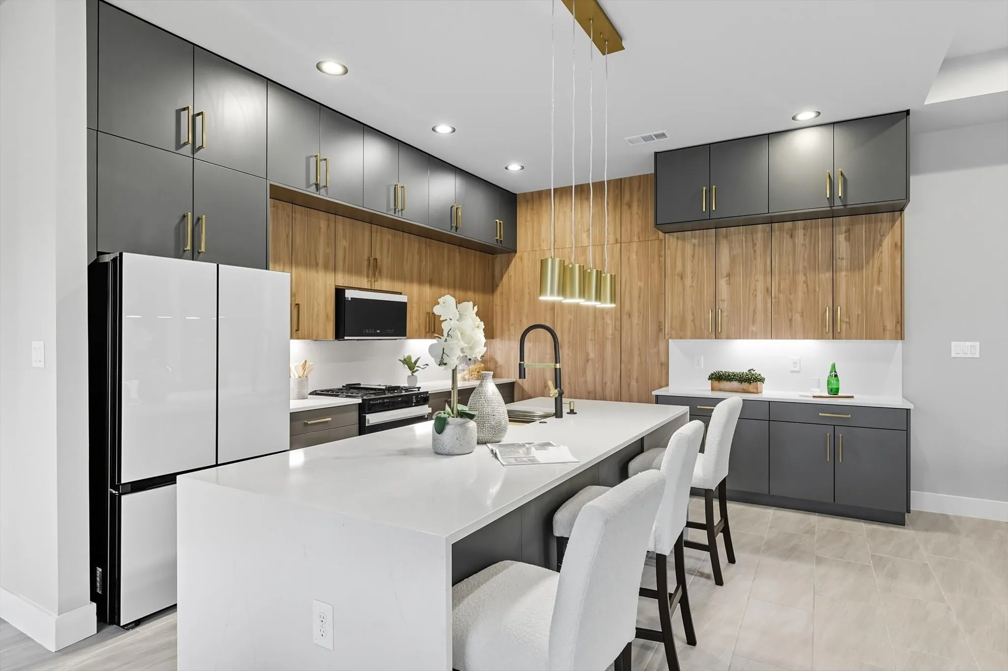 Kitchen with freestanding refrigerator, a kitchen breakfast bar, black gas range, a center island with sink, and modern cabinets