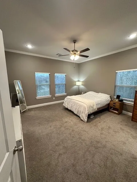 Carpeted bedroom featuring crown molding, ceiling fan, and recessed lighting