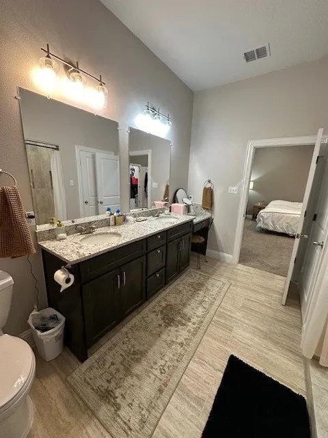 Bathroom featuring double vanity, ensuite bathroom, and curtained shower