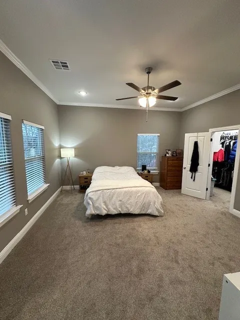 Bedroom with carpet floors, crown molding, a walk in closet, ceiling fan, and recessed lighting
