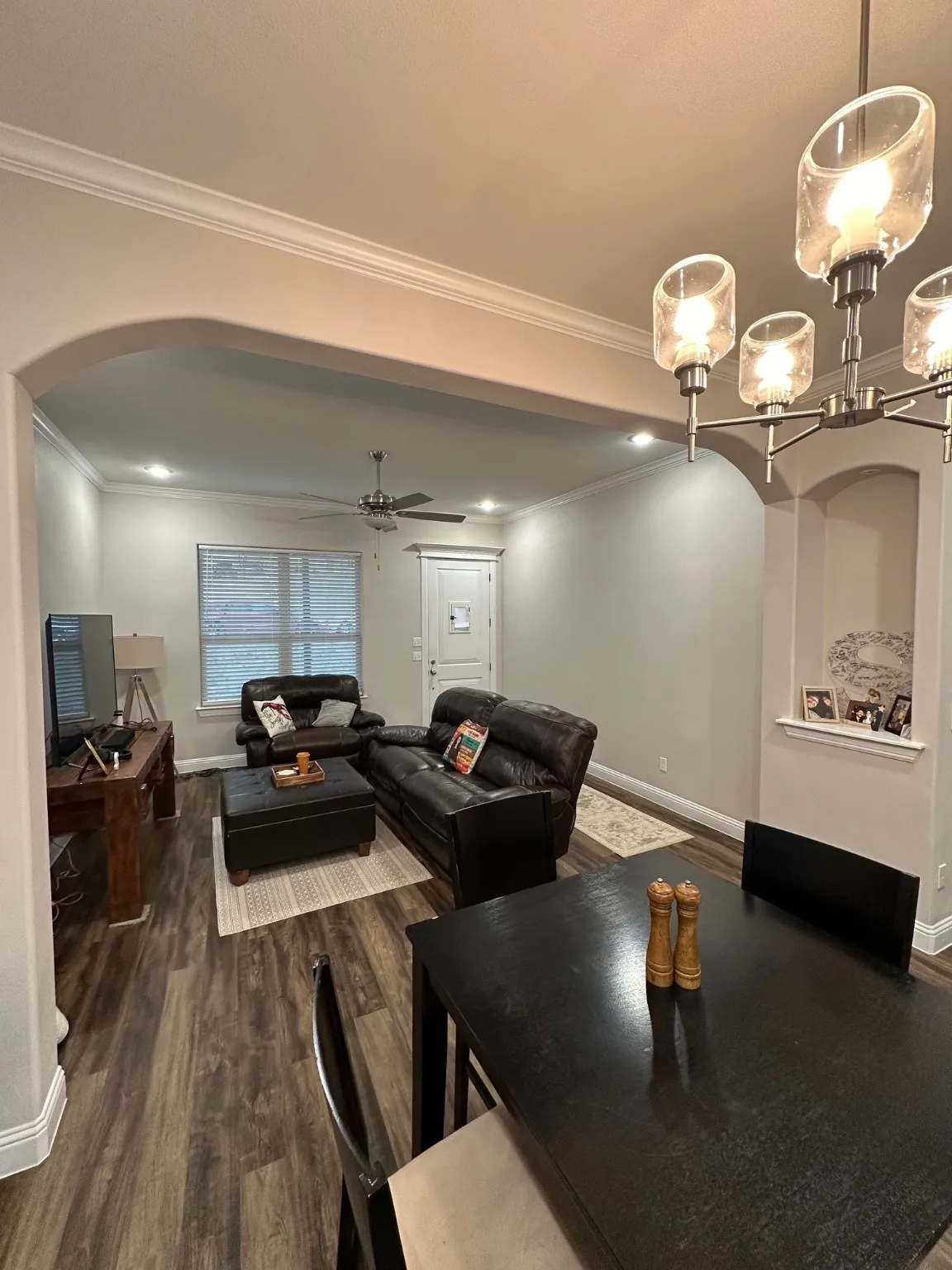 Dining room with arched walkways, crown molding, dark wood-type flooring, a ceiling fan, and a chandelier