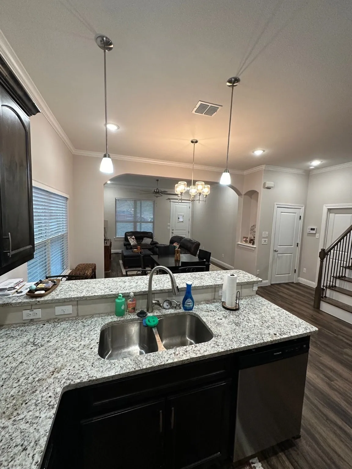 Kitchen featuring open floor plan, crown molding, light stone counters, dark wood-style floors, and dishwasher