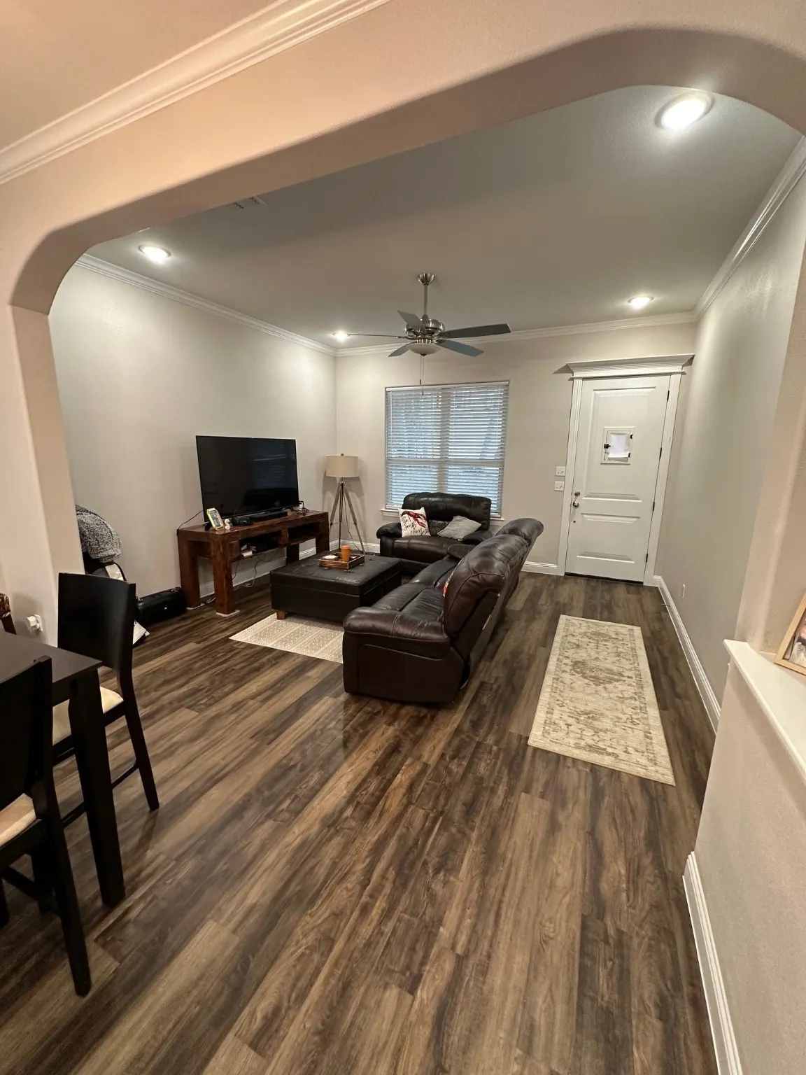 Living area featuring arched walkways, ornamental molding, dark wood-style flooring, and recessed lighting