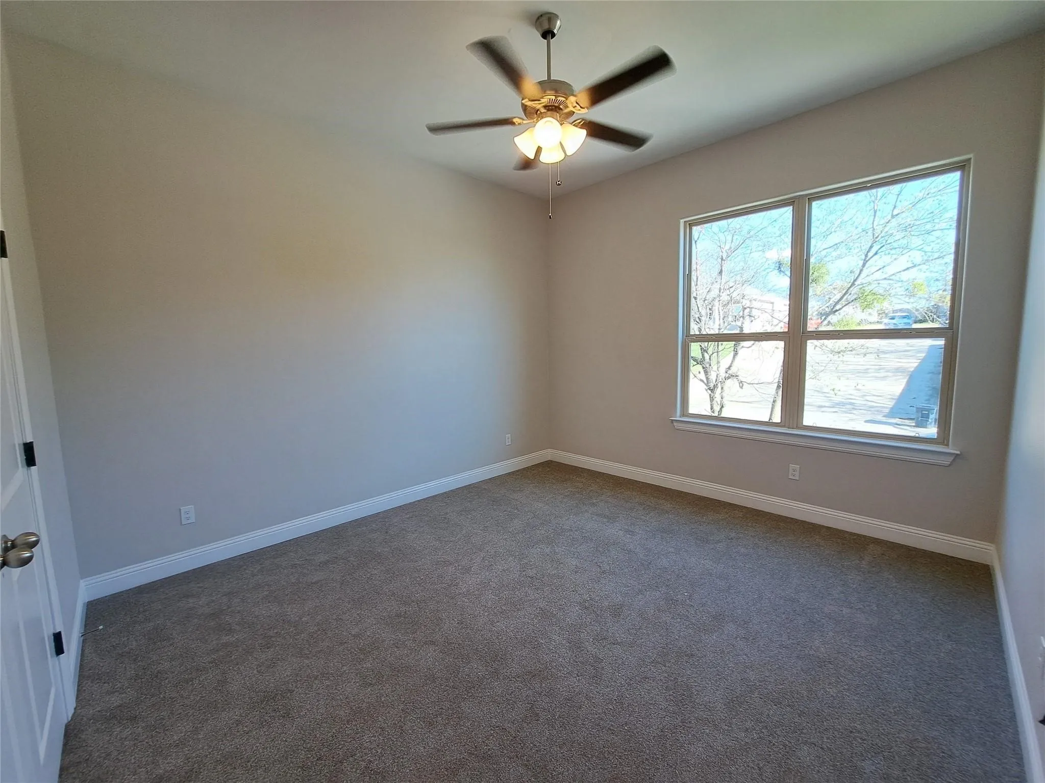 Carpeted empty room featuring baseboards and ceiling fan