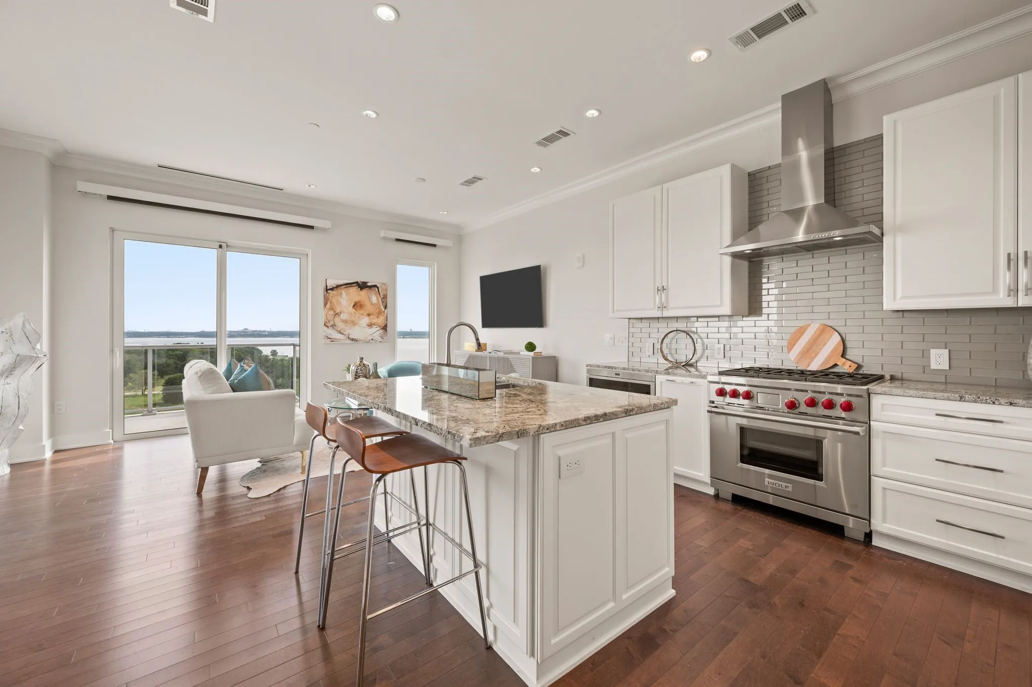 Kitchen with white cabinets, ornamental molding, light stone countertops, designer range, and tasteful backsplash