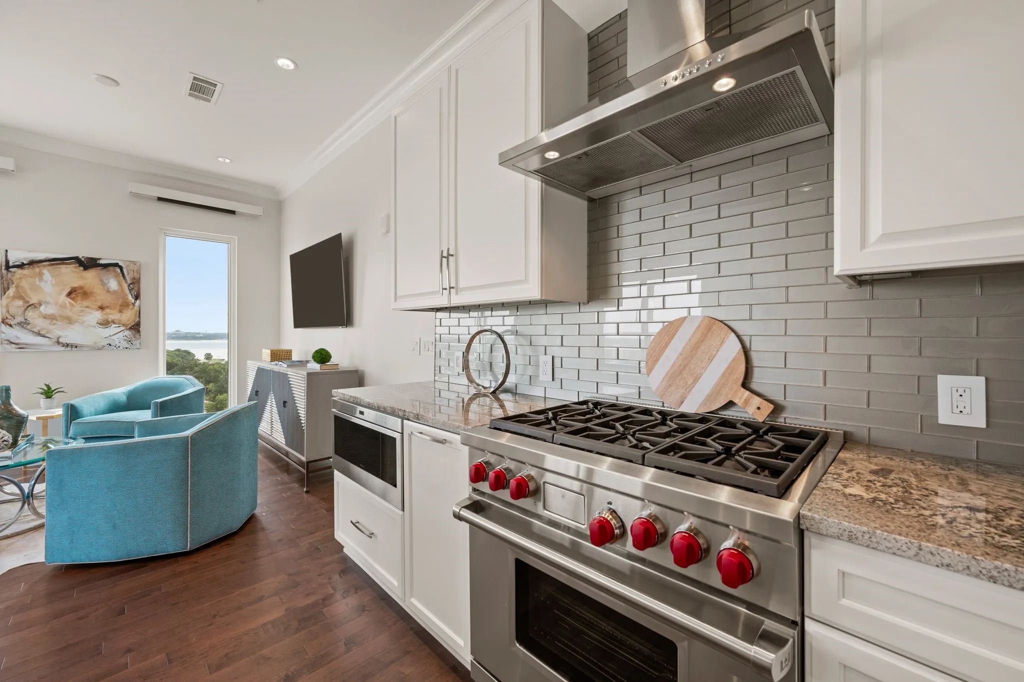 Kitchen featuring appliances with stainless steel finishes, white cabinetry, wall chimney range hood, crown molding, and decorative backsplash
