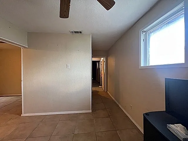 Hallway featuring a textured ceiling and tile patterned floors