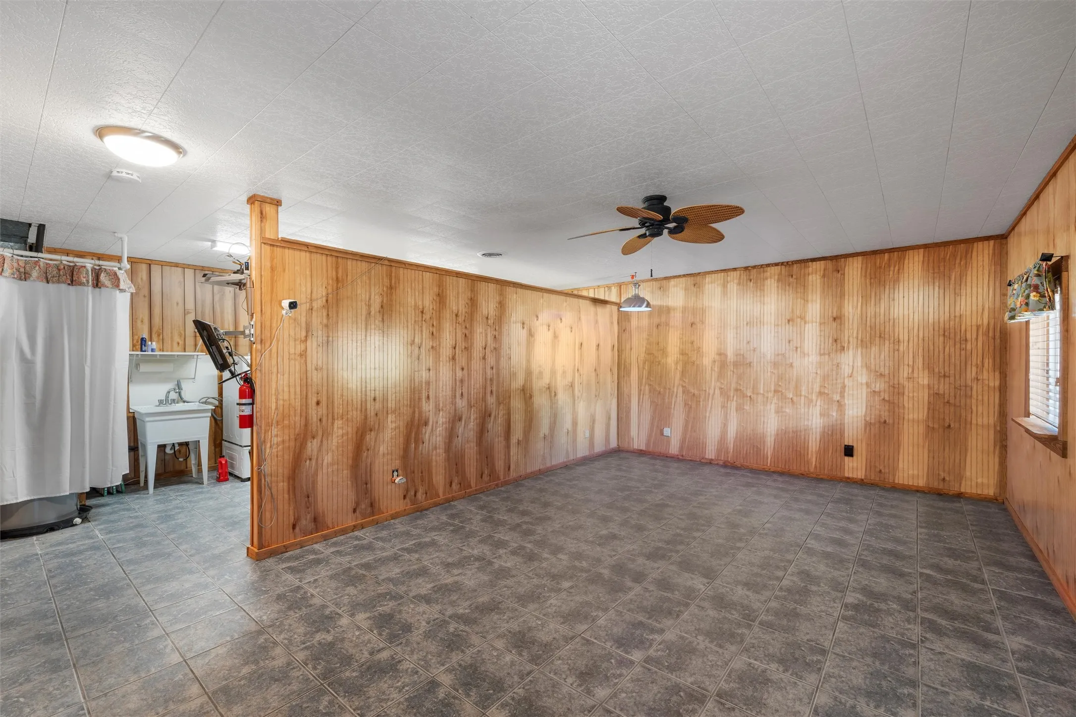 Unfurnished living room featuring wooden walls and a ceiling fan