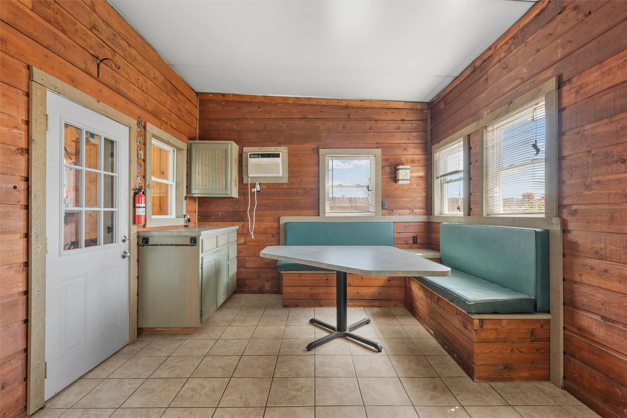 Office space featuring wooden walls, light tile patterned flooring, and a wall unit AC