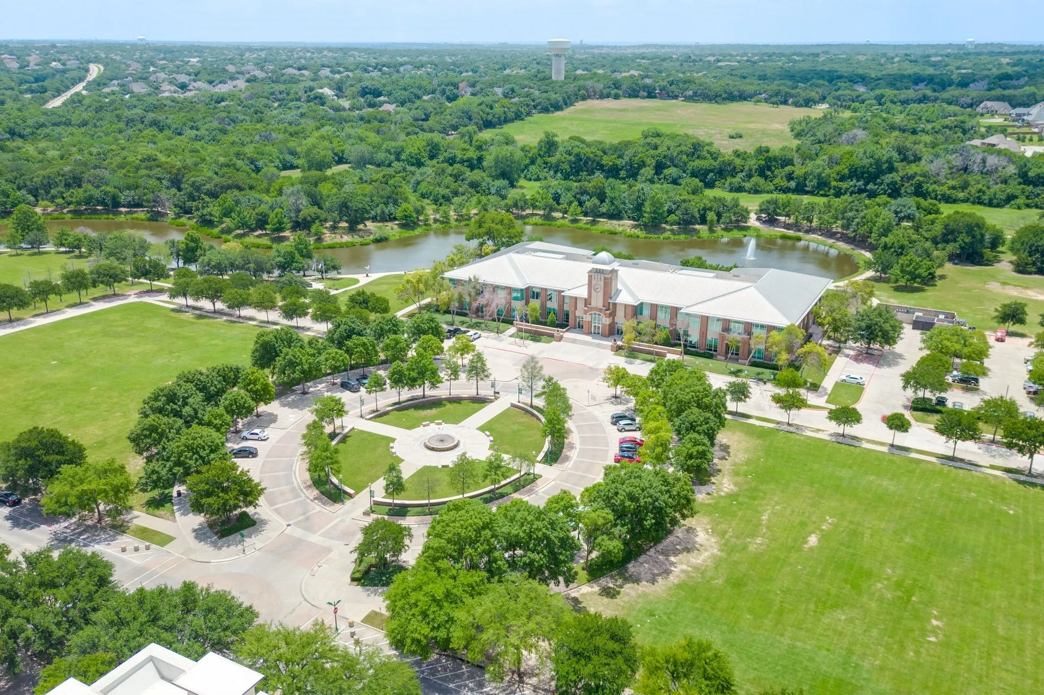 Drone / aerial view of a nearby body of water and a tree filled landscape