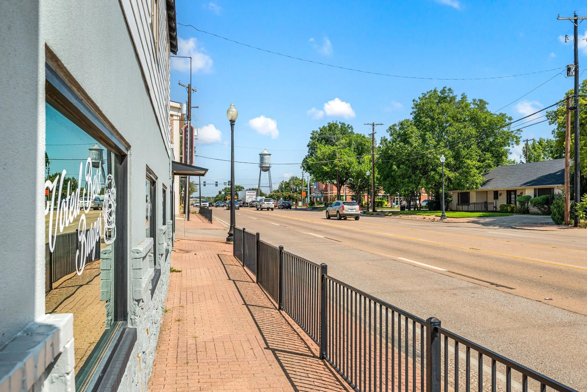 View of asphalt road with sidewalks, curbs, and street lights