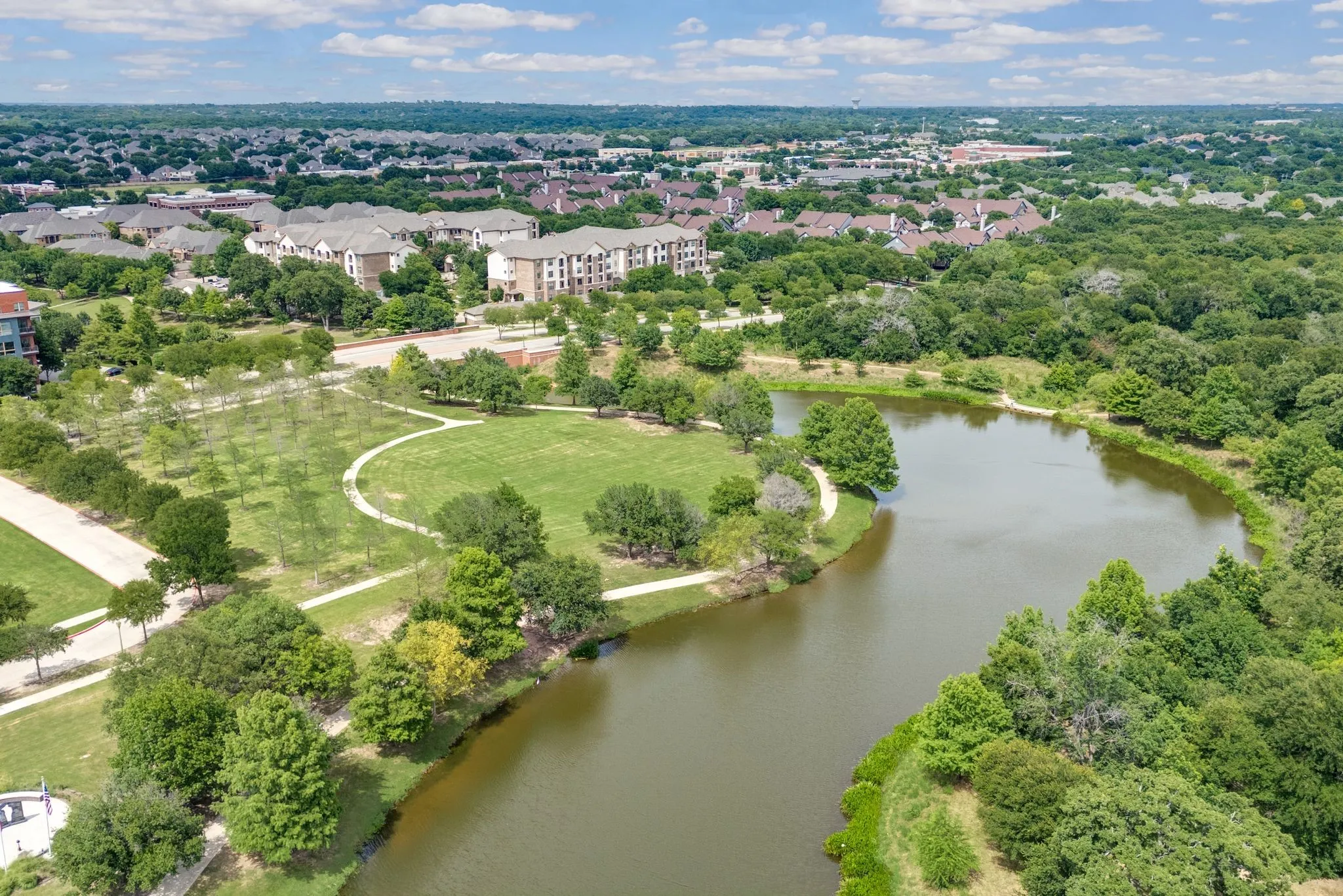 Drone / aerial view of a nearby body of water and a tree filled landscape