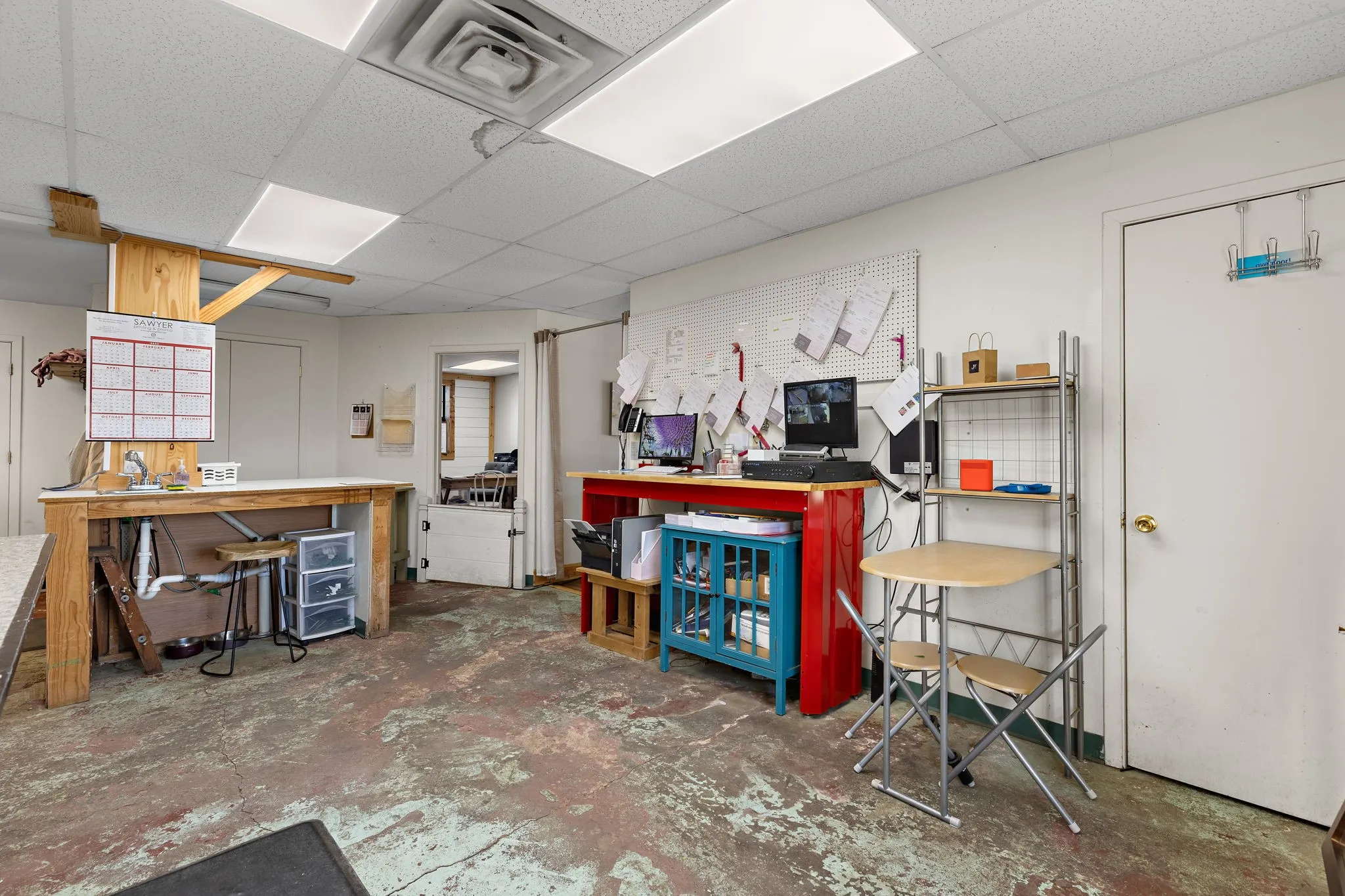 Misc room featuring a workshop area, concrete flooring, and a paneled ceiling