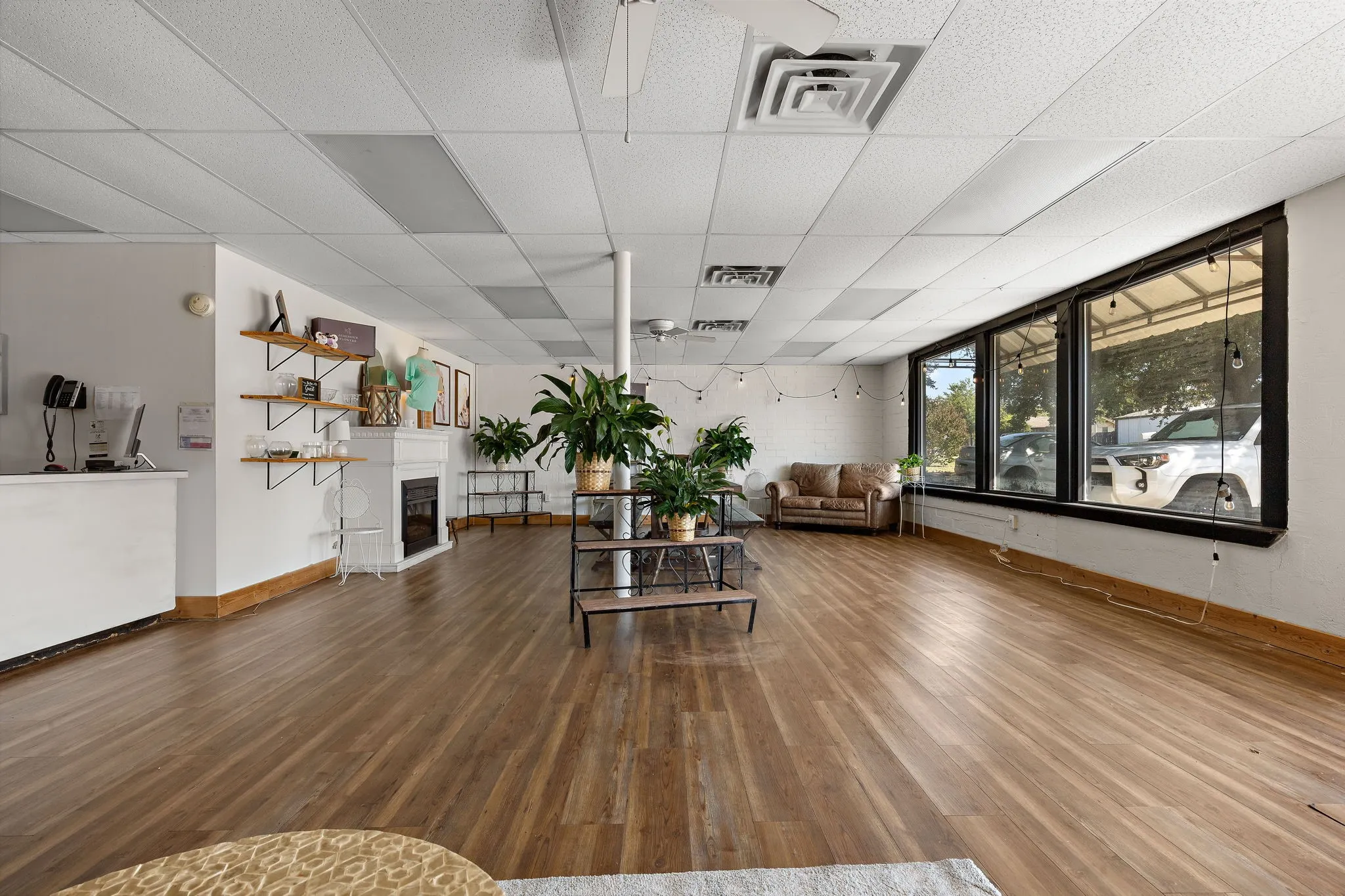 Living room with a paneled ceiling, wood finished floors, and a glass covered fireplace