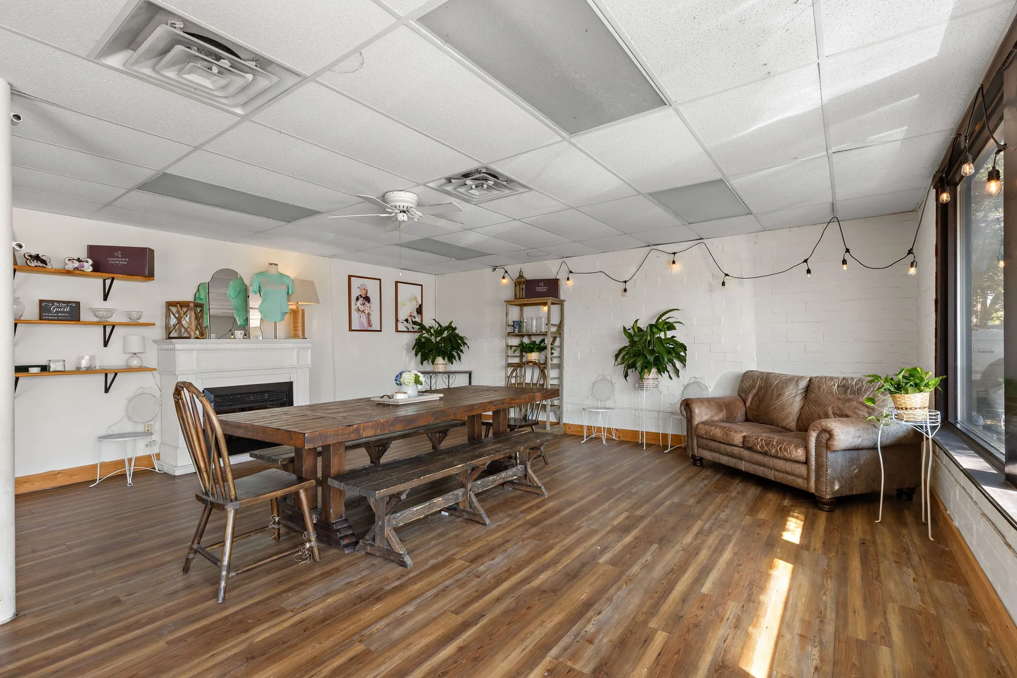 Dining area with dark wood-type flooring, ceiling fan, a paneled ceiling, and a fireplace