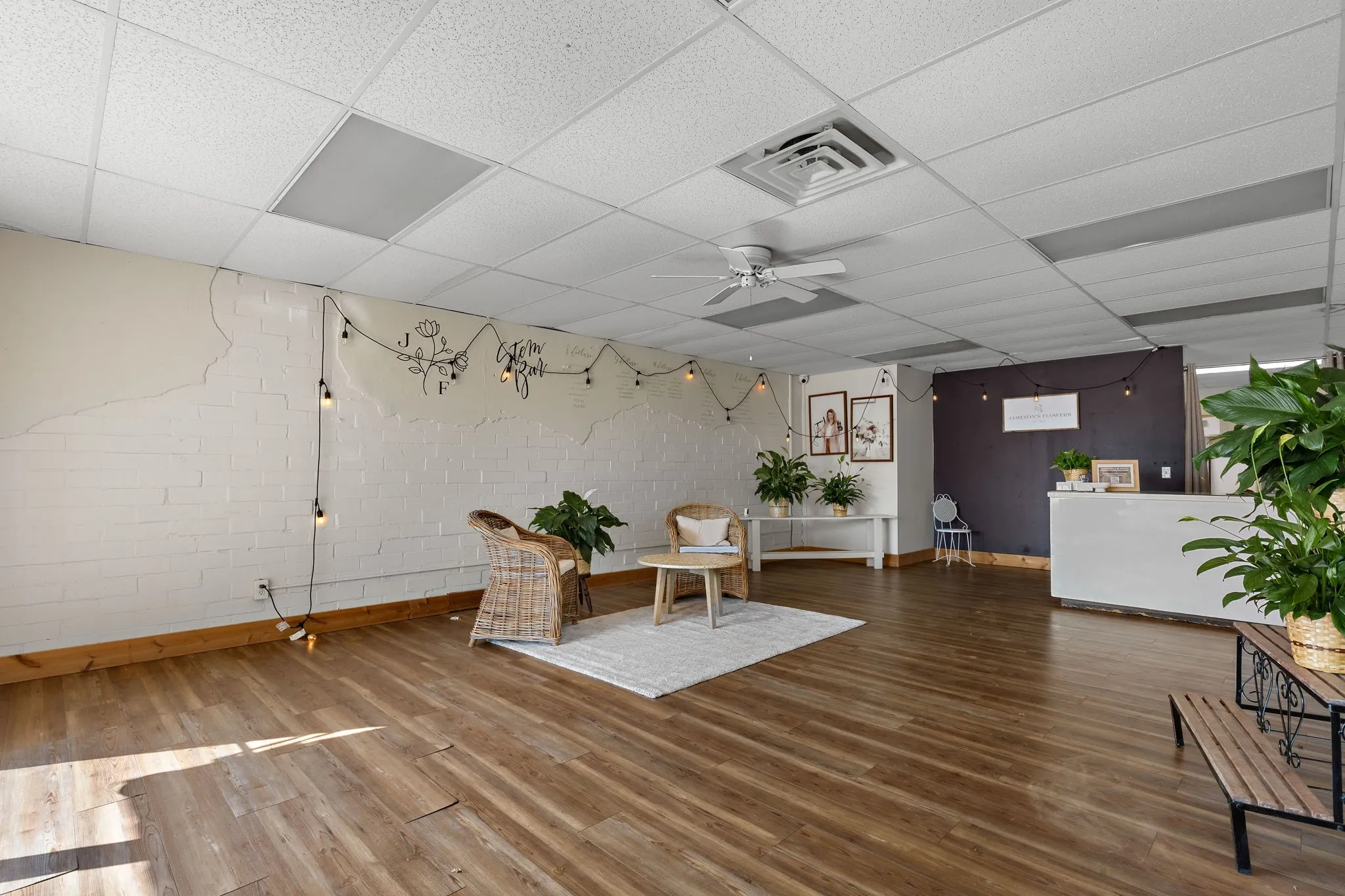 Sitting room with a ceiling fan, wood finished floors, and a drop ceiling