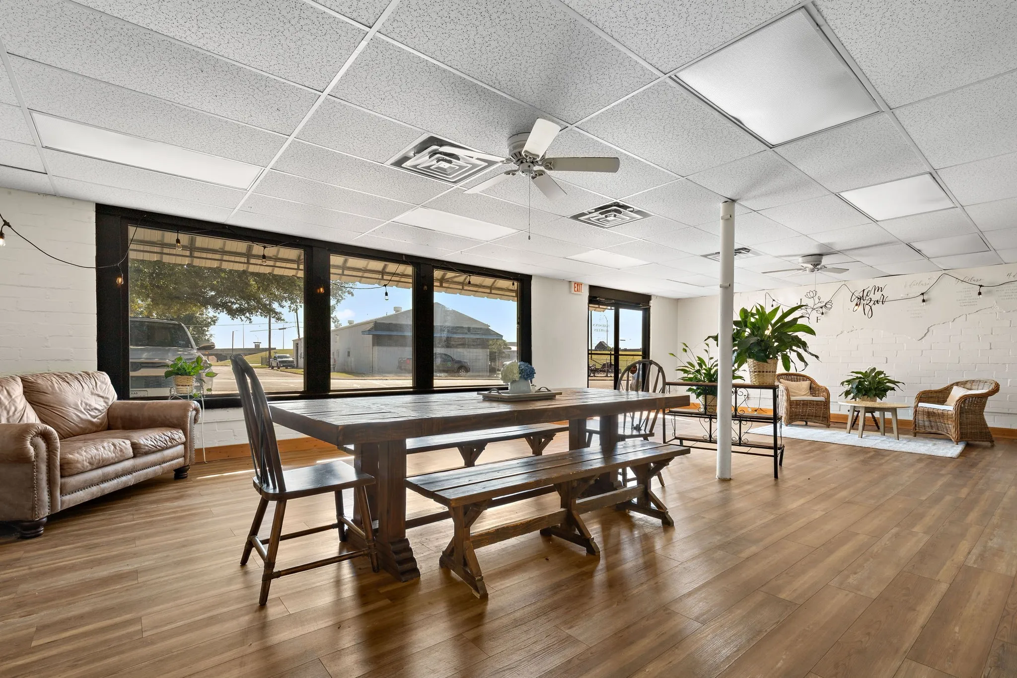 Dining space with ceiling fan, a drop ceiling, and wood finished floors