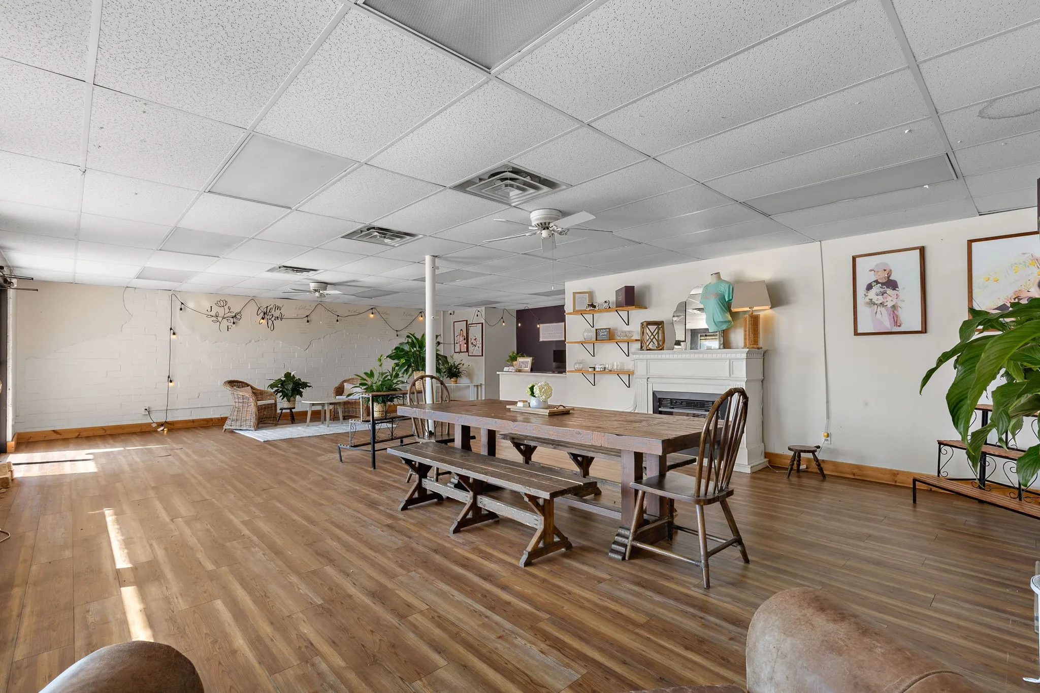Dining room featuring a drop ceiling, wood finished floors, a fireplace, and a ceiling fan