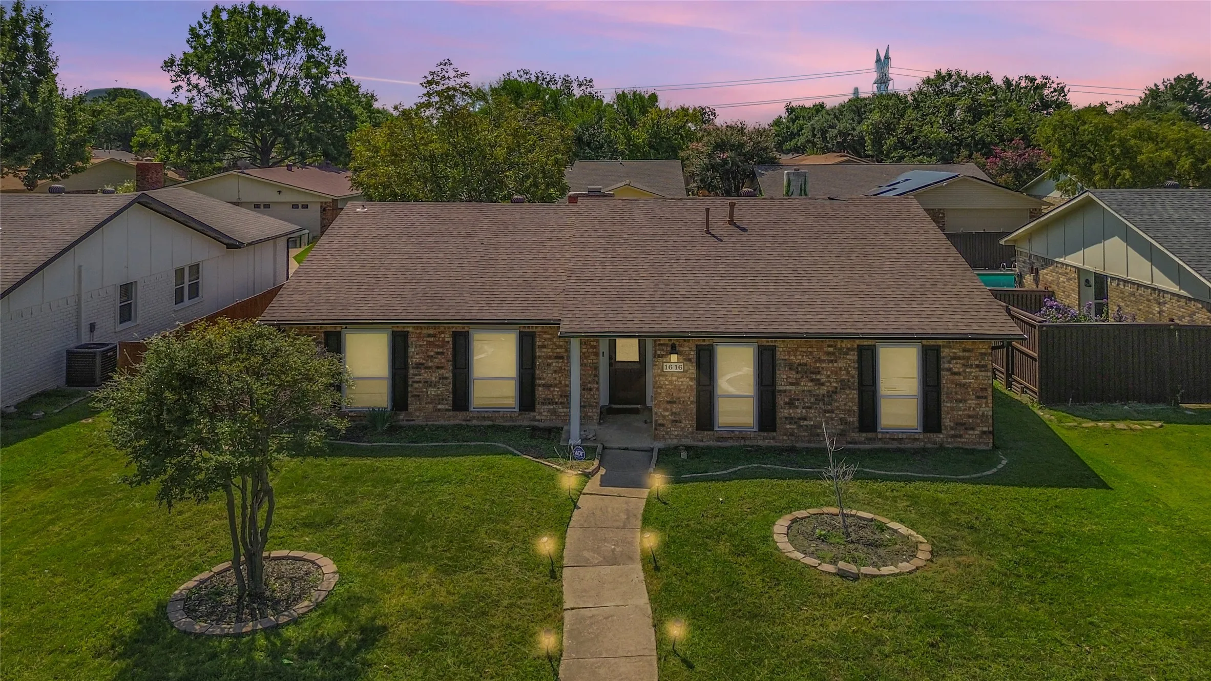 View of front of property featuring a shingled roof, brick siding, and a lawn