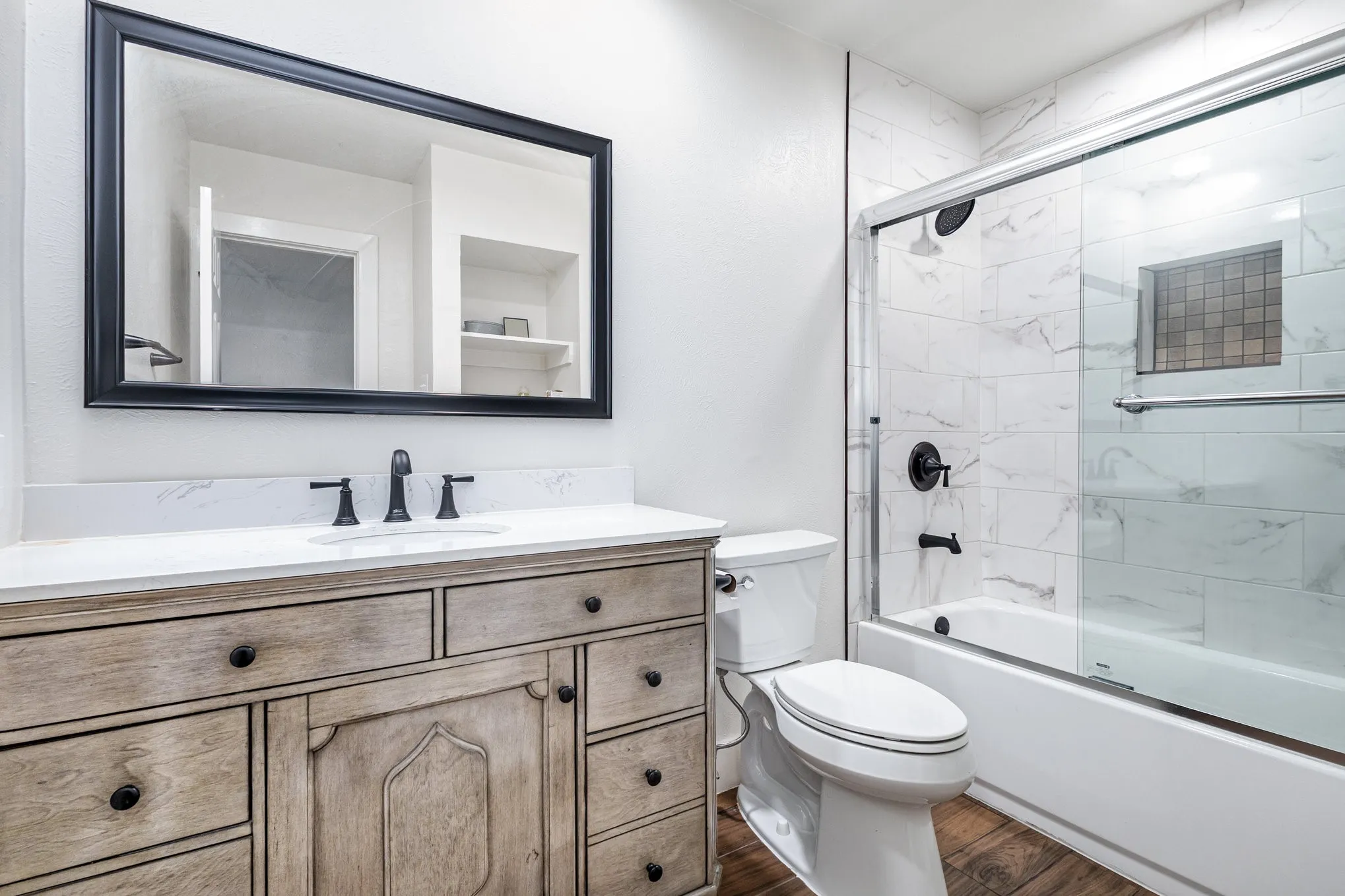Bathroom with bath / shower combo with glass door, vanity, and dark wood-style flooring