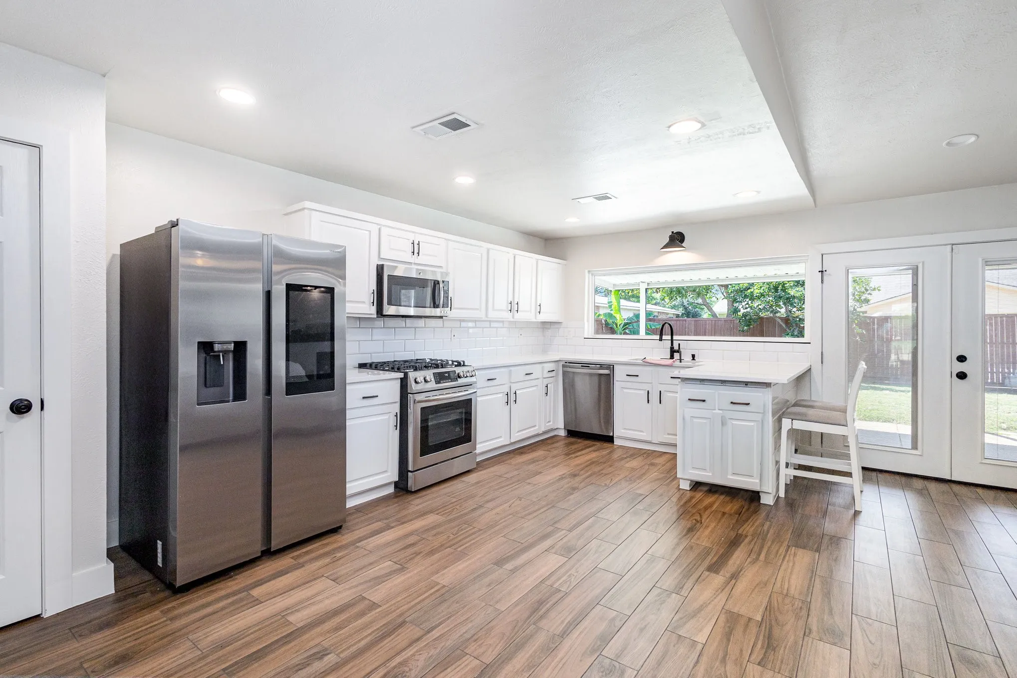 Kitchen featuring tasteful backsplash, appliances with stainless steel finishes, white cabinetry, french doors, and recessed lighting