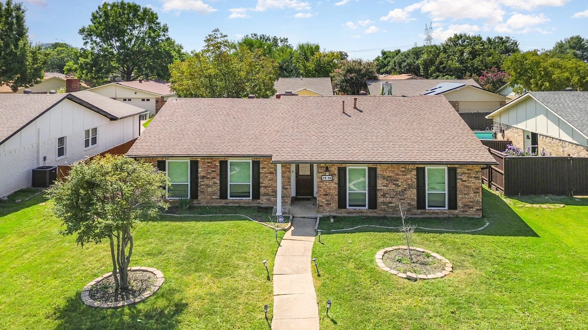 View of front of property with a shingled roof and brick siding
