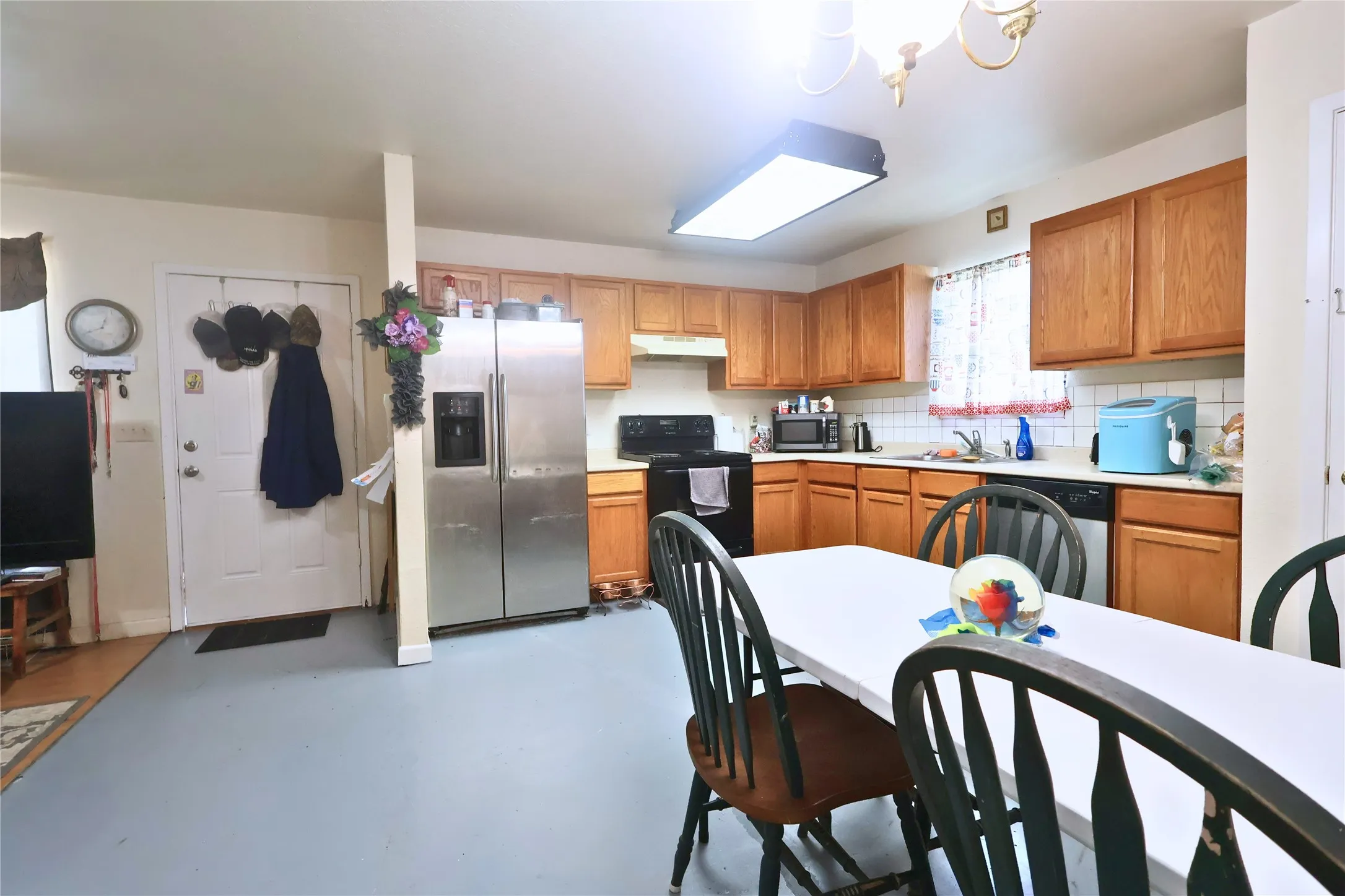 Kitchen with light countertops, appliances with stainless steel finishes, finished concrete flooring, and brown cabinets