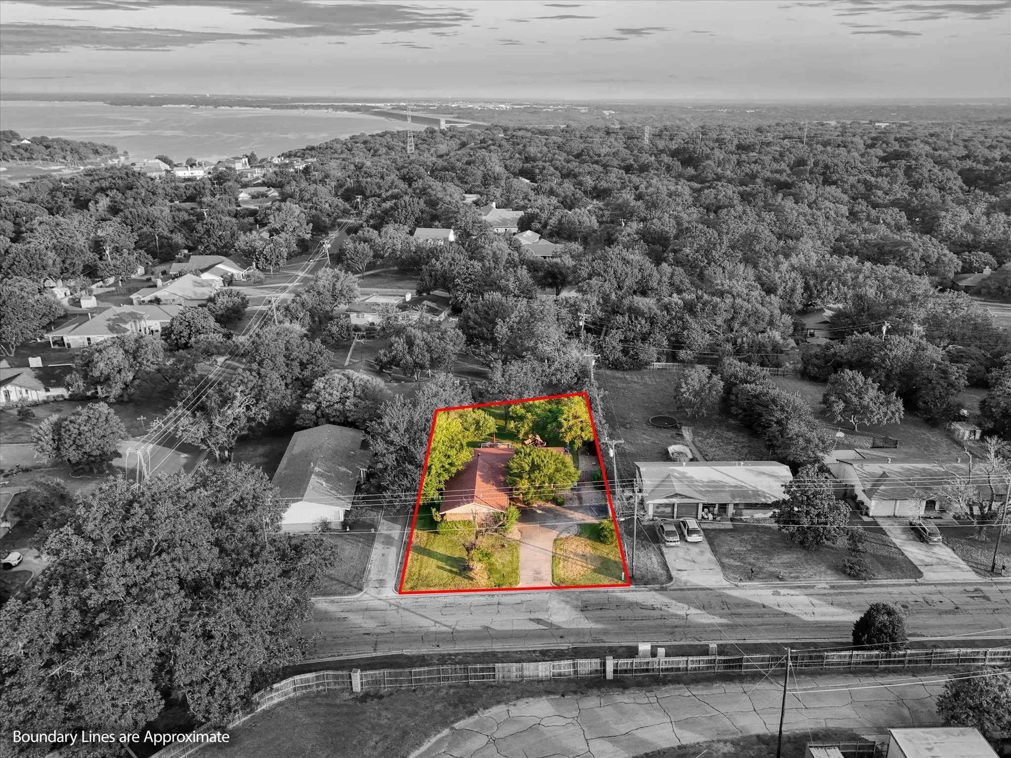 Aerial perspective of suburban area with a heavily wooded area and property boundaries highlighted