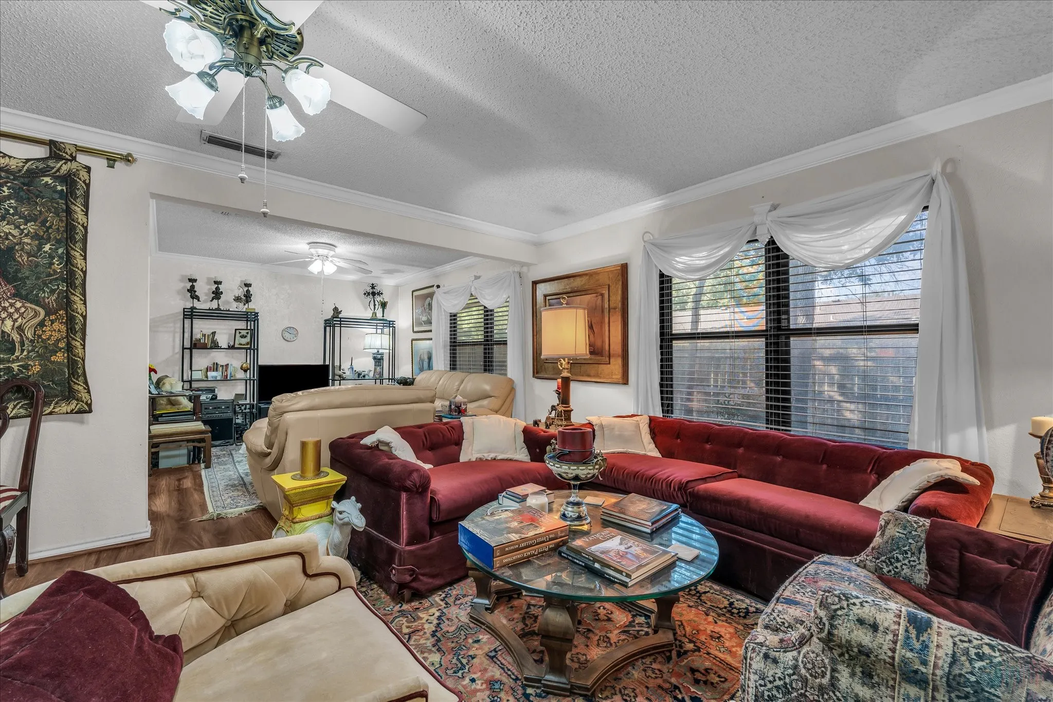Living room featuring a textured ceiling, wood finished floors, ornamental molding, and ceiling fan