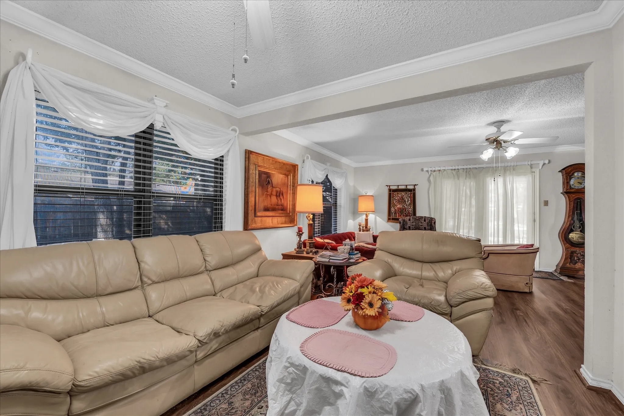 Living room featuring ceiling fan, a textured ceiling, crown molding, and wood finished floors