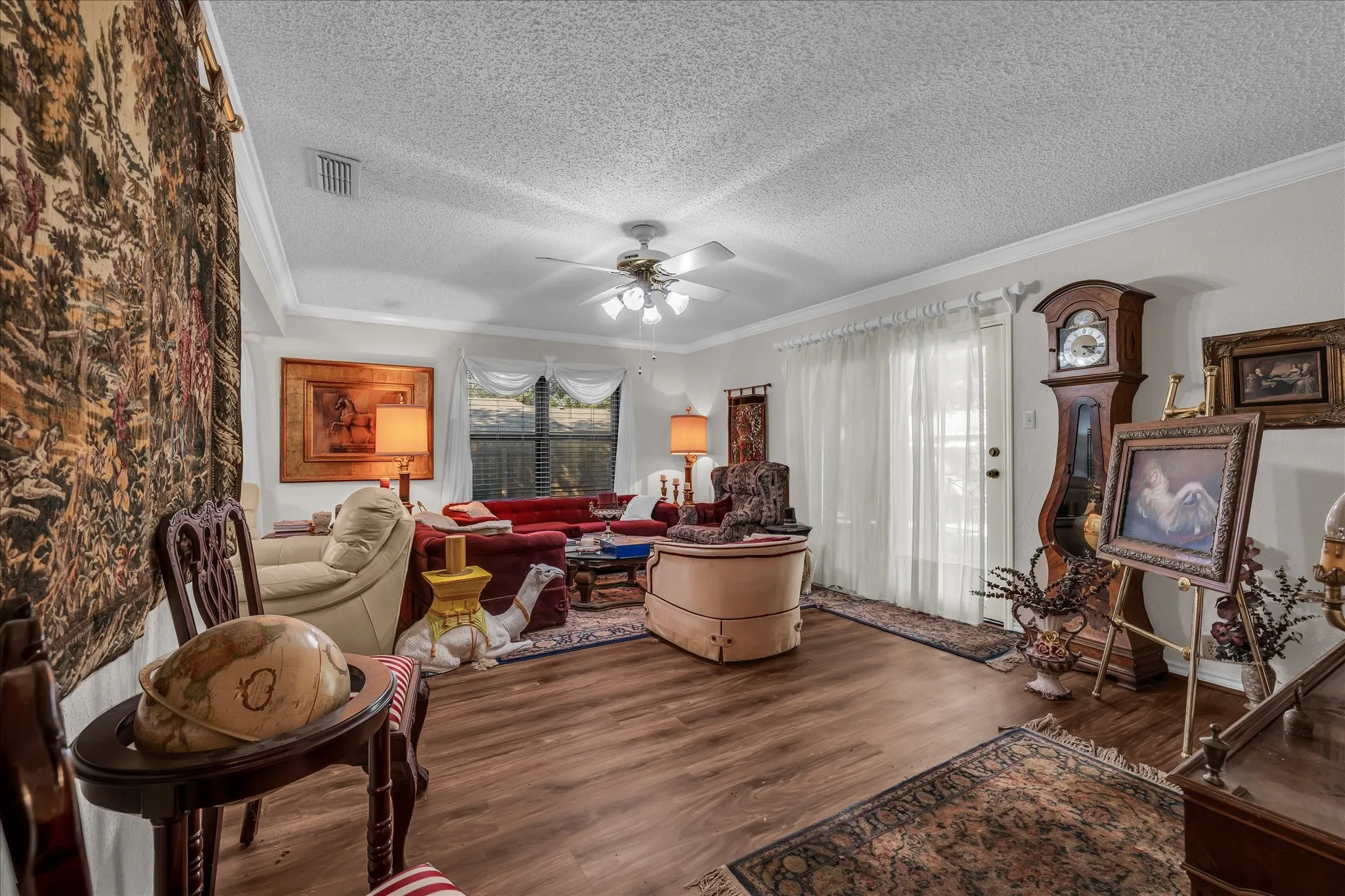 Living area with wood finished floors, crown molding, a textured ceiling, and ceiling fan