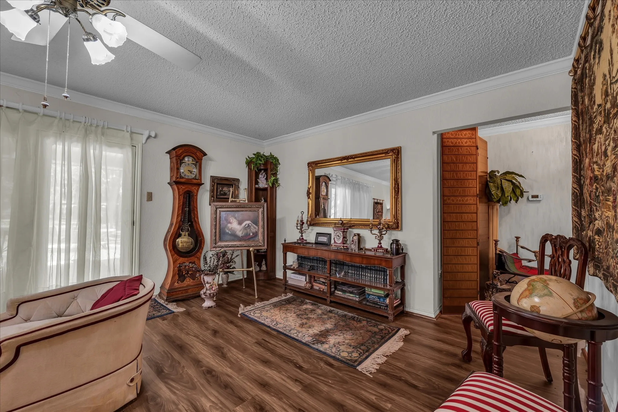 Sitting room with crown molding, dark wood-style flooring, a textured ceiling, and a ceiling fan