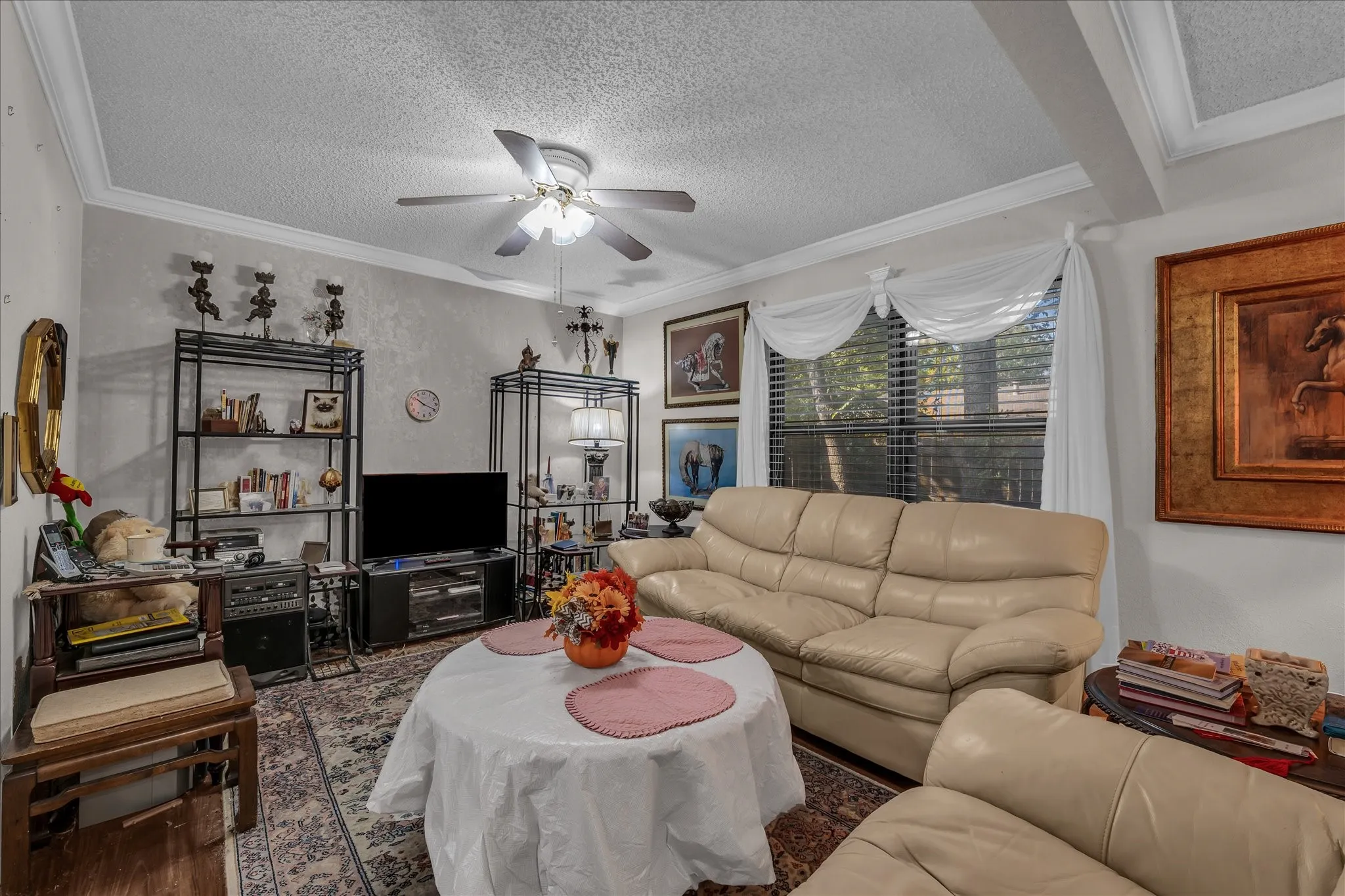 Living area featuring a textured ceiling, ornamental molding, ceiling fan, and wood finished floors
