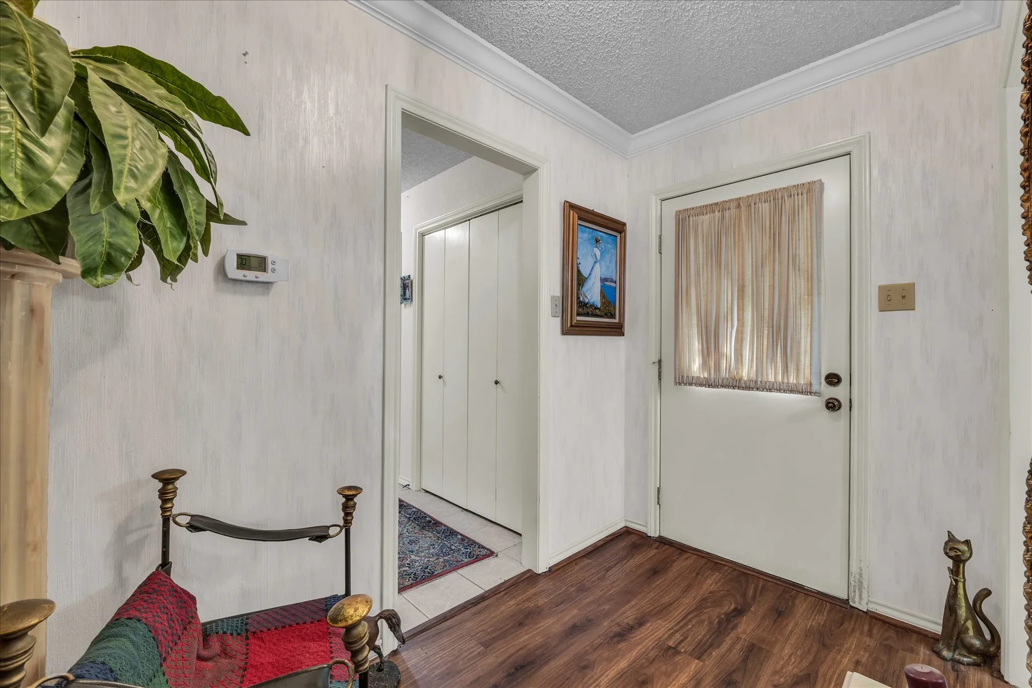 Entryway featuring ornamental molding, dark wood-type flooring, and a textured ceiling