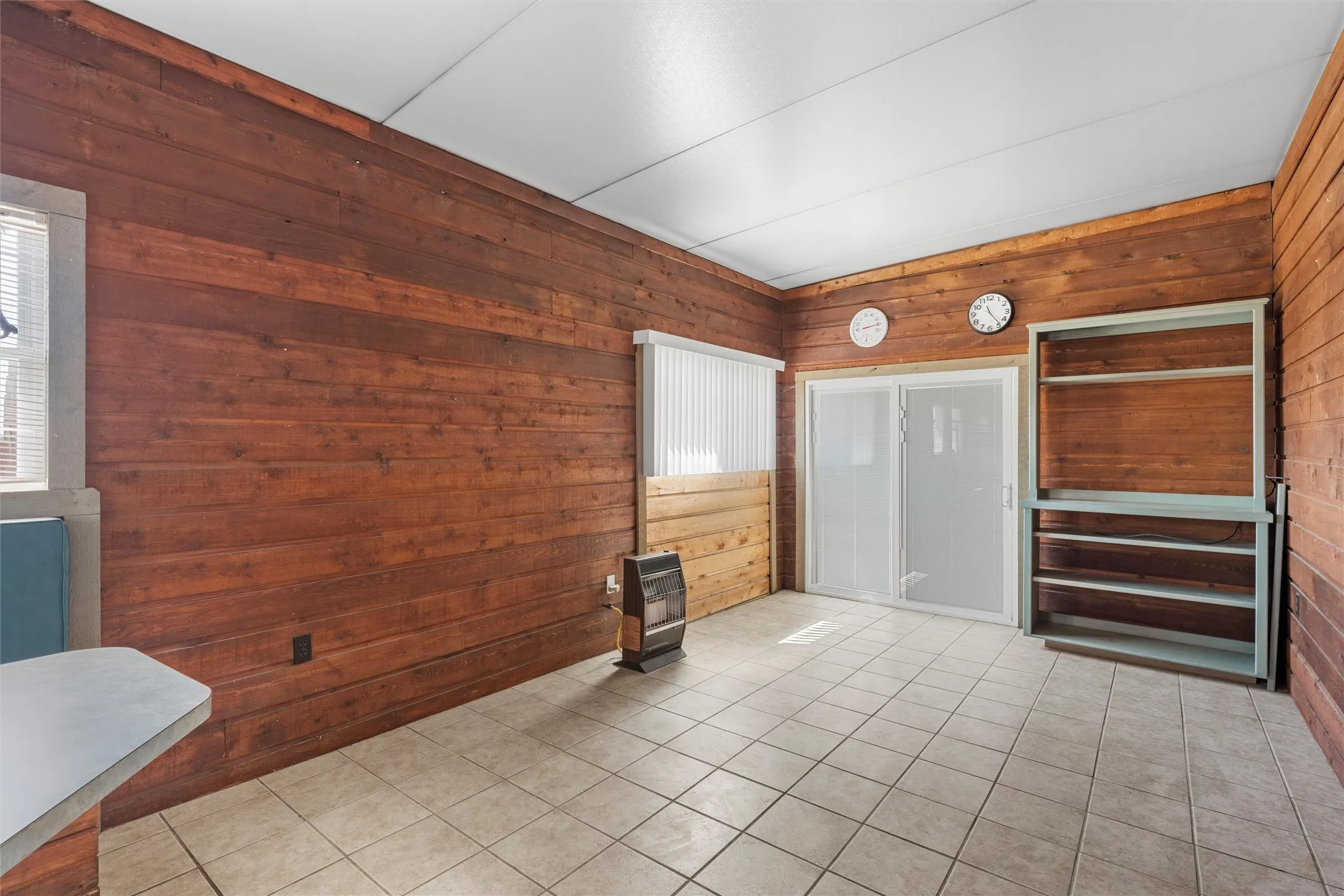 Unfurnished room featuring wooden walls, light tile patterned floors, and heating unit