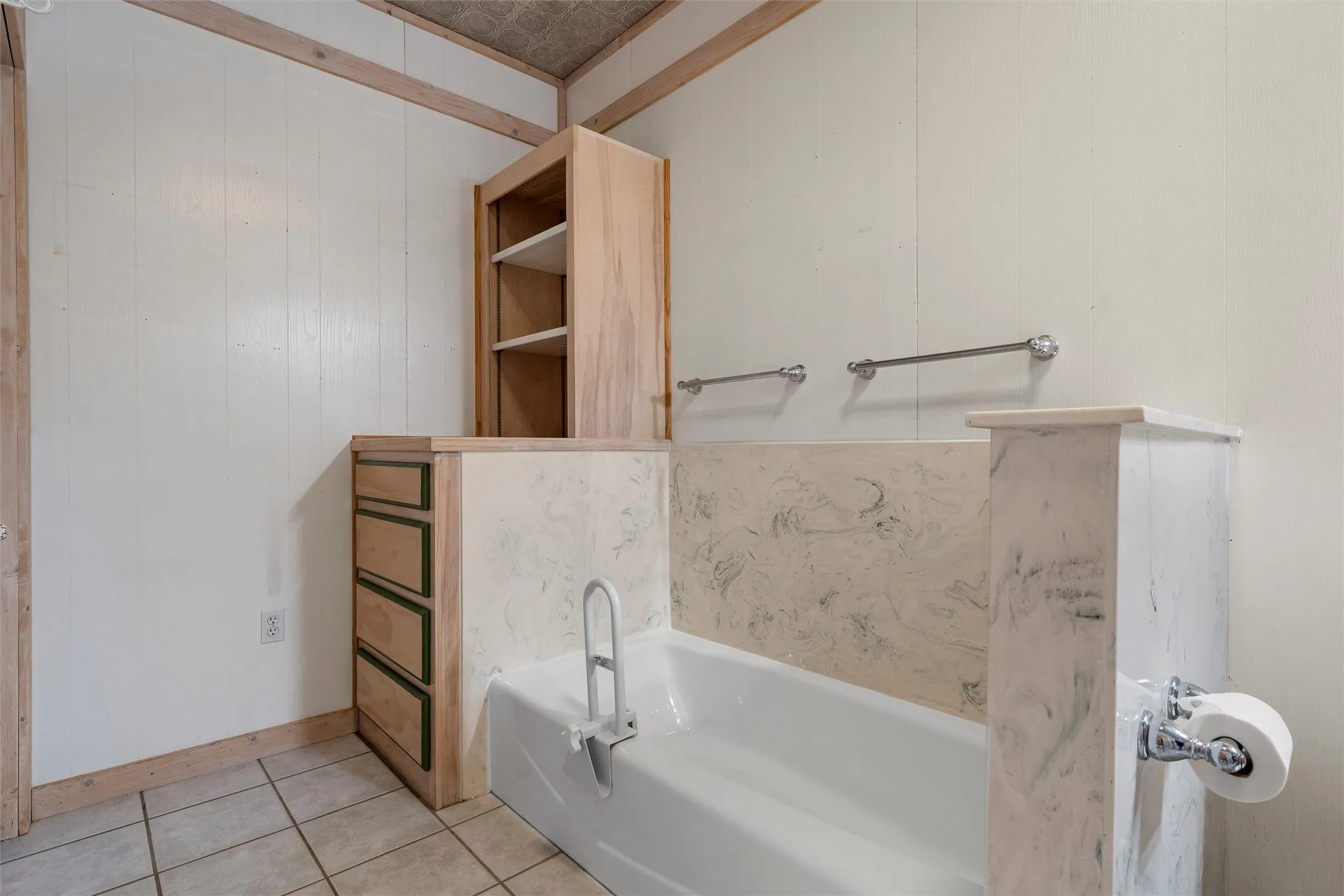 Bathroom featuring a bath, light tile patterned floors, and wood walls