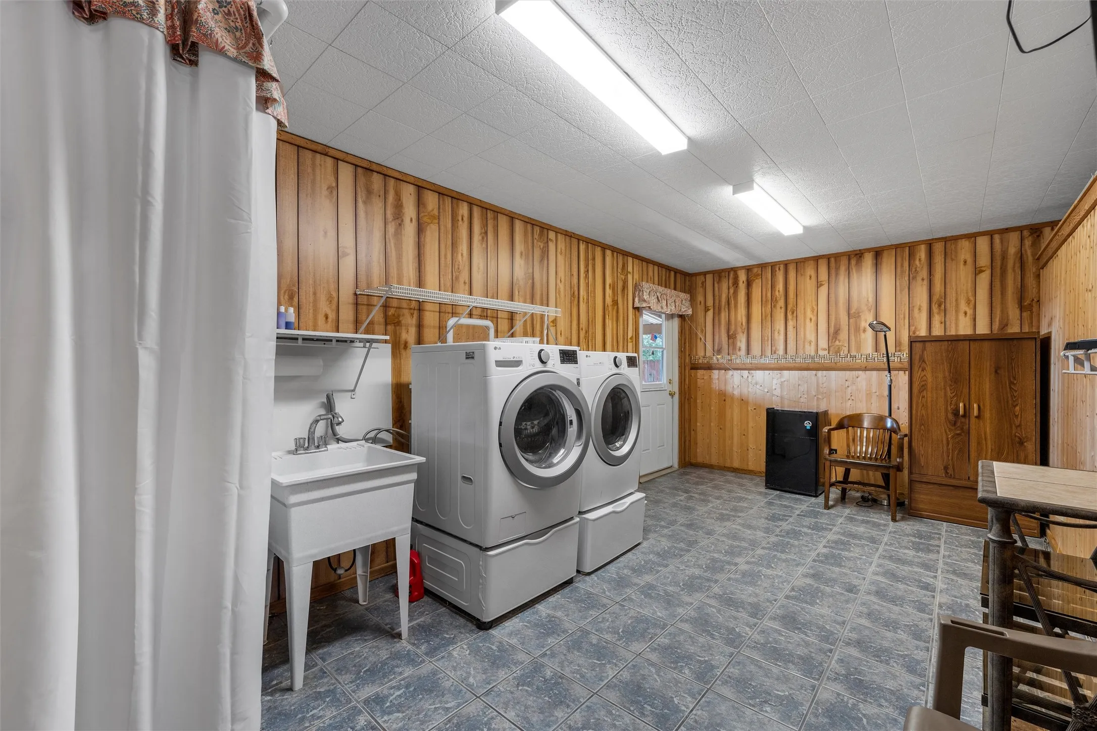 Washroom featuring wood walls, washing machine and dryer, and dark flooring