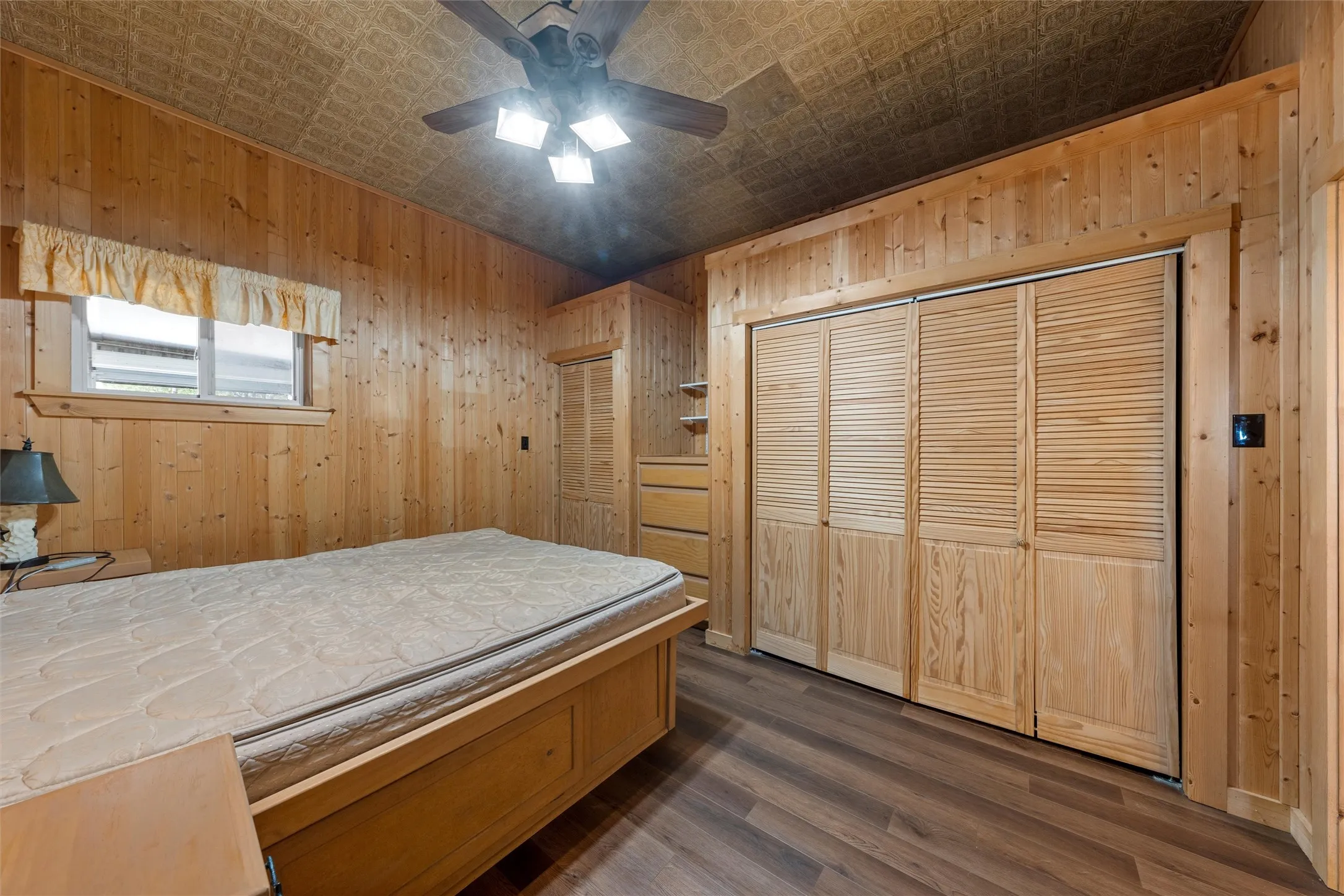 Bedroom with an ornate ceiling, wooden walls, dark wood-style flooring, a closet, and ceiling fan