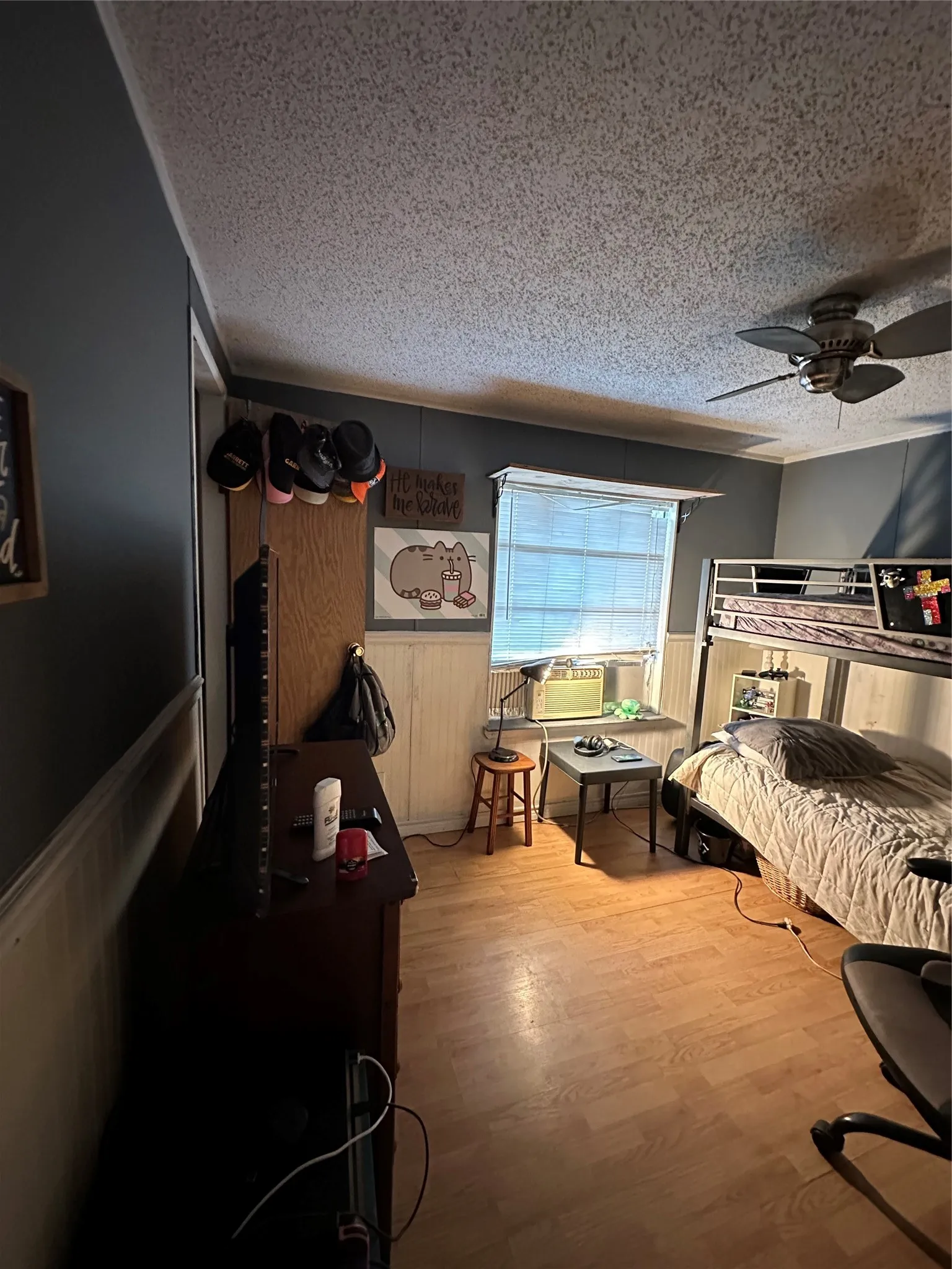 Bedroom featuring a wainscoted wall, light wood-type flooring, a textured ceiling, wooden walls, and ceiling fan
