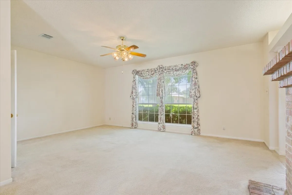 Unfurnished living room with light colored carpet and ceiling fan