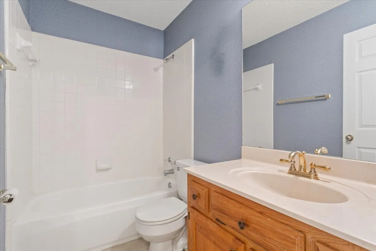 Full bathroom featuring bathing tub / shower combination, vanity, a textured ceiling, and a textured wall