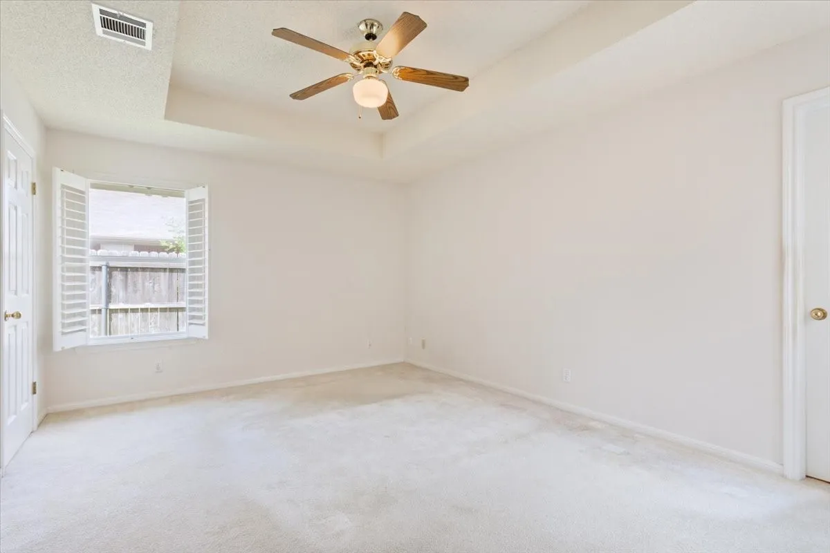 Carpeted spare room with a raised ceiling and a ceiling fan