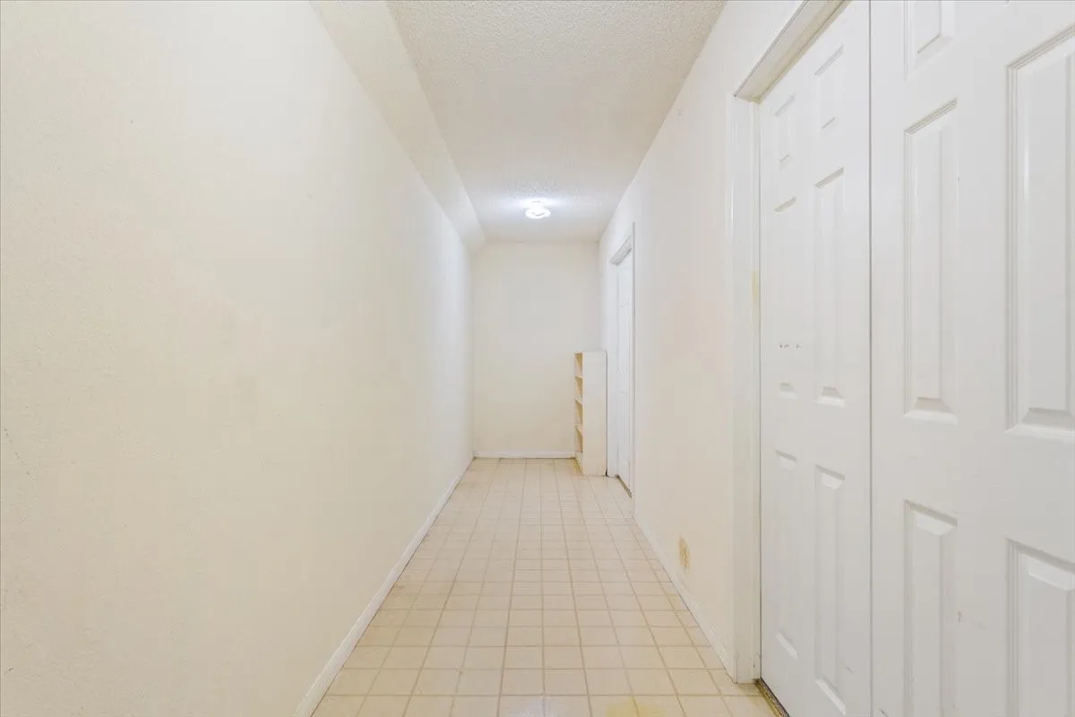 Hallway featuring a textured ceiling and light tile patterned flooring