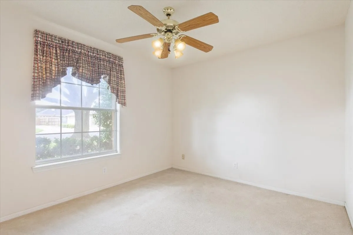 Carpeted empty room with baseboards and ceiling fan