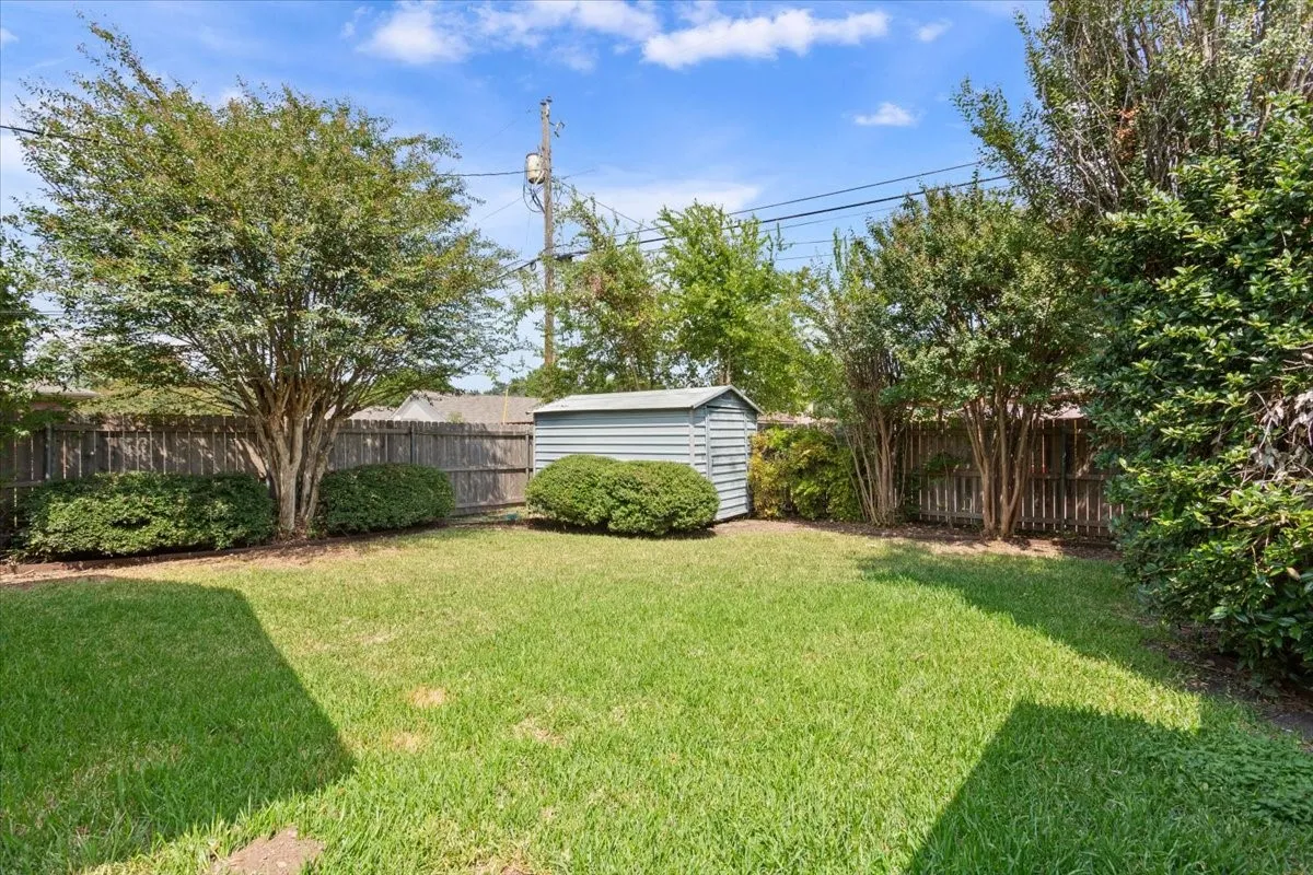 Fenced backyard featuring a storage shed