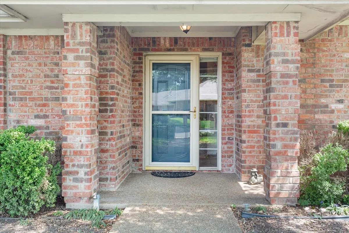 Property entrance featuring brick siding and covered porch