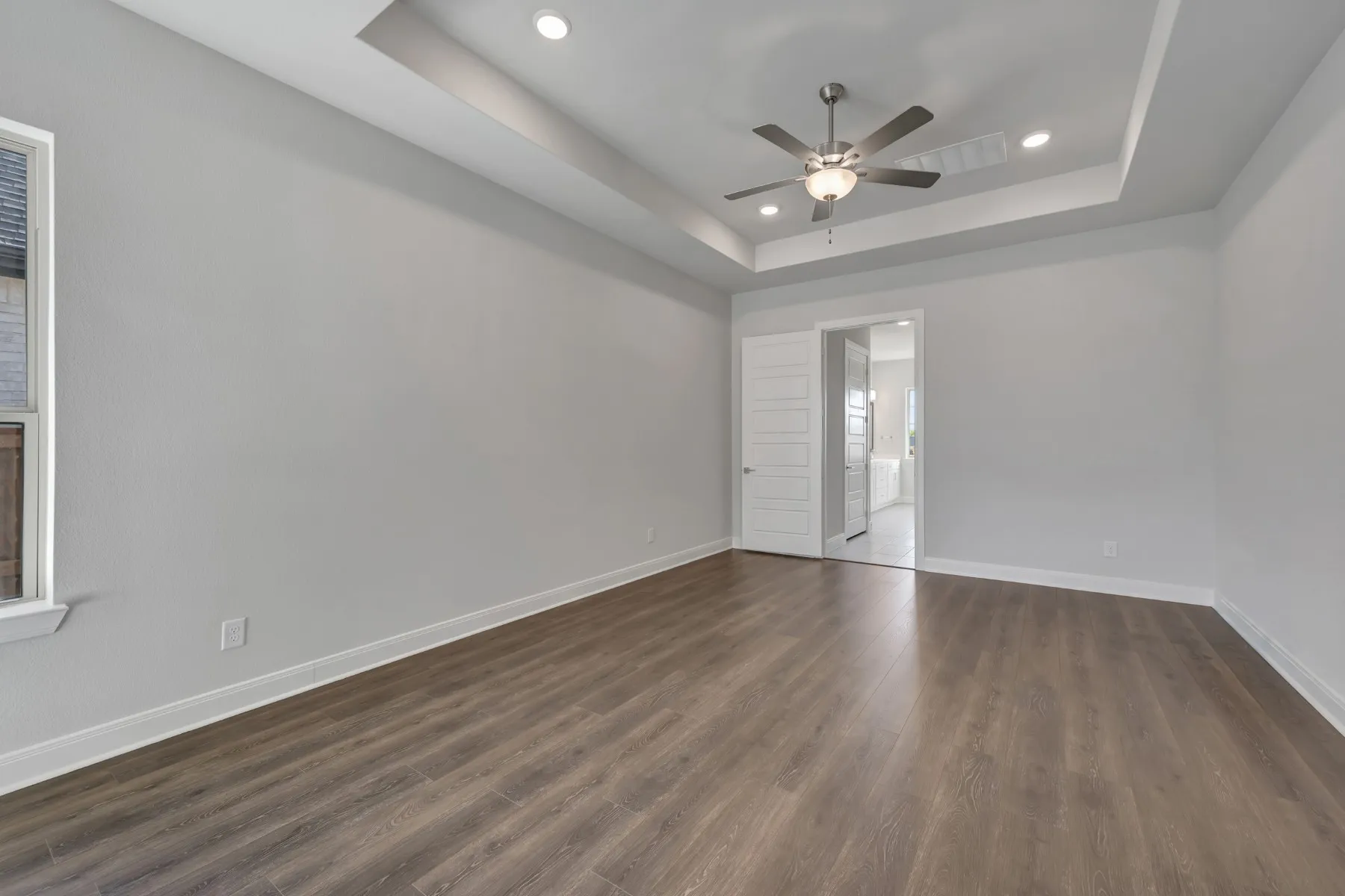 Spare room featuring a ceiling fan, dark wood-style floors, recessed lighting, and a raised ceiling
